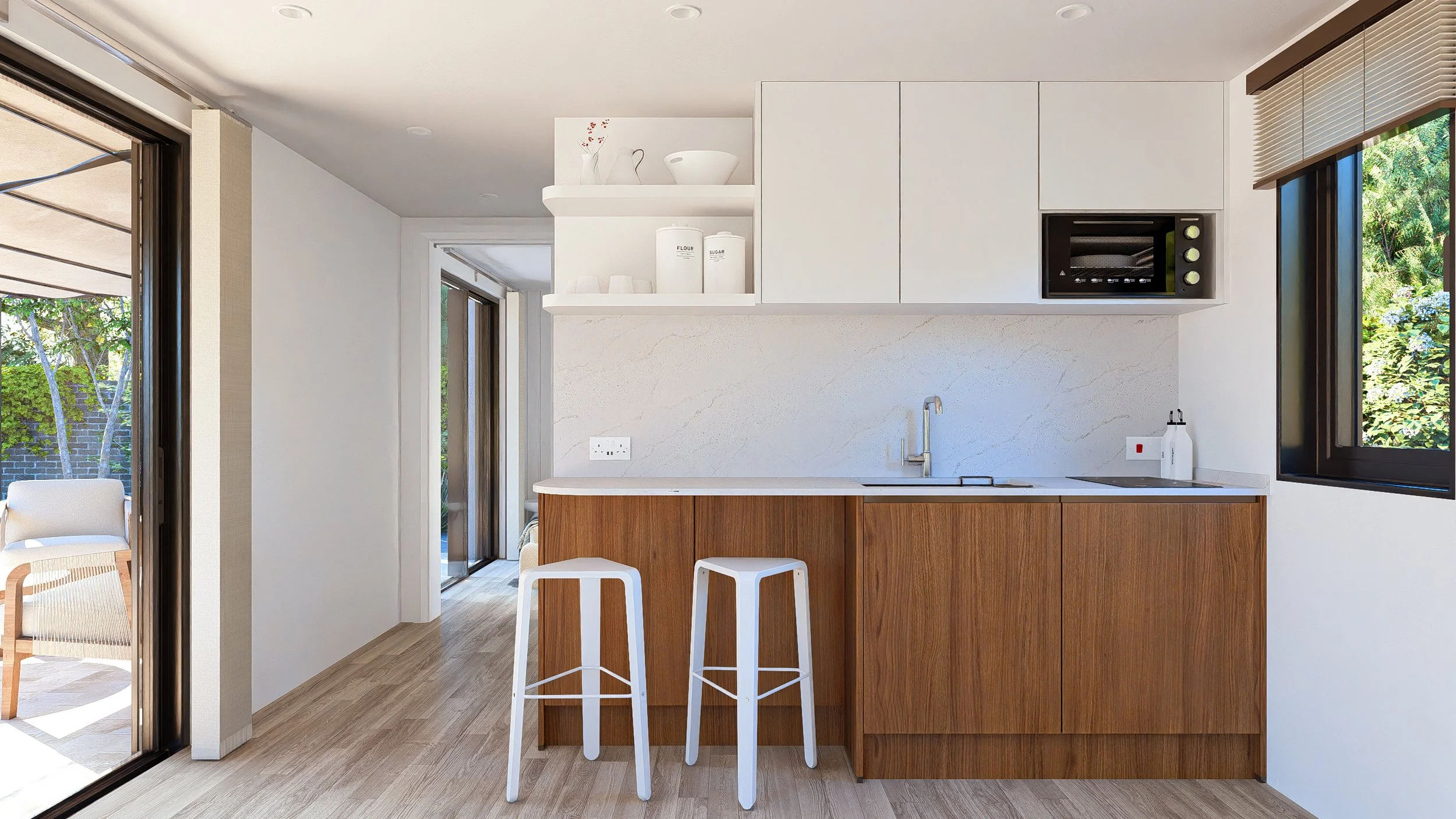 Bauhu hurricane resistant modular hospitality pod  kitchen with white upper cabinets, wooden lower cabinets, two white bar stools, a marble backsplash, and a window showing greenery outside