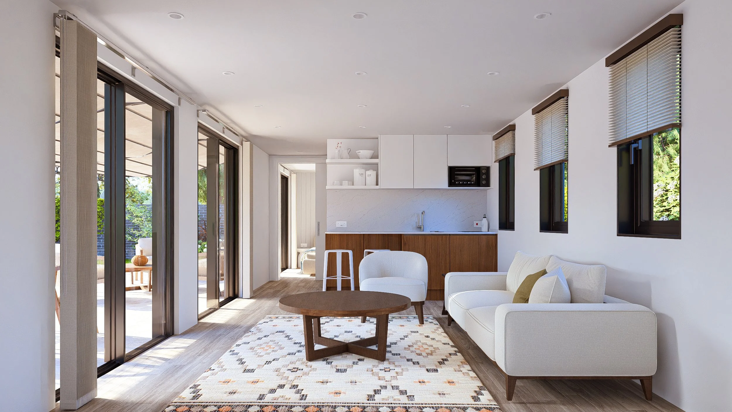 Bauhu hurricane resistant modular hospitality pod  living room with white sofa, armchair, wooden coffee table, patterned rug, and kitchen in the background. Large glass sliding doors lead to an outdoor patio.