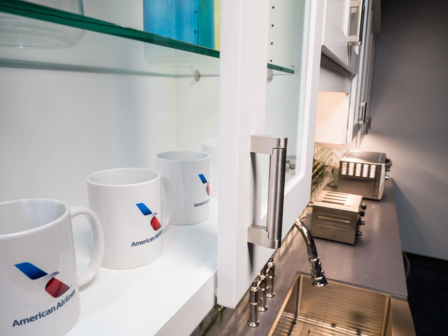 American Airlines branded coffee mugs on display in a kitchen or kitchenette area.