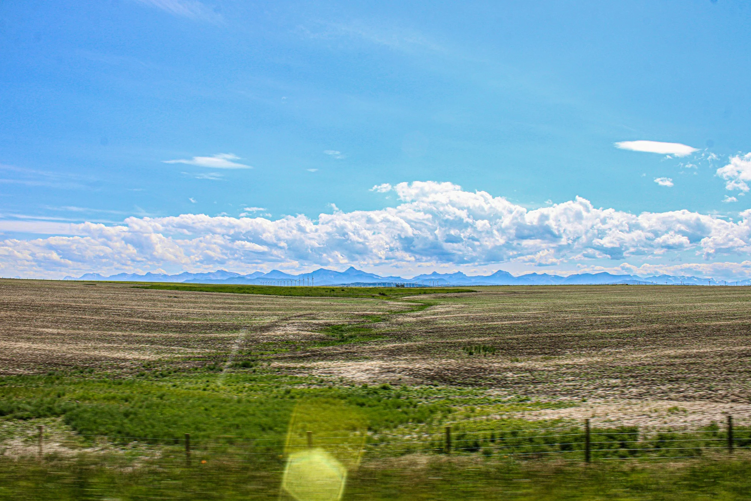Wide Alberta prairie under big sky with the Rocky Mountains on the horizon, home to clients of a Canadian virtual assistant team