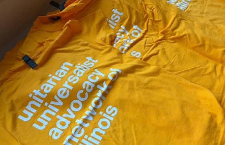 A few gold T shirts with white lettering The words are Unitarian Universalist Advocacy Network of Illinois