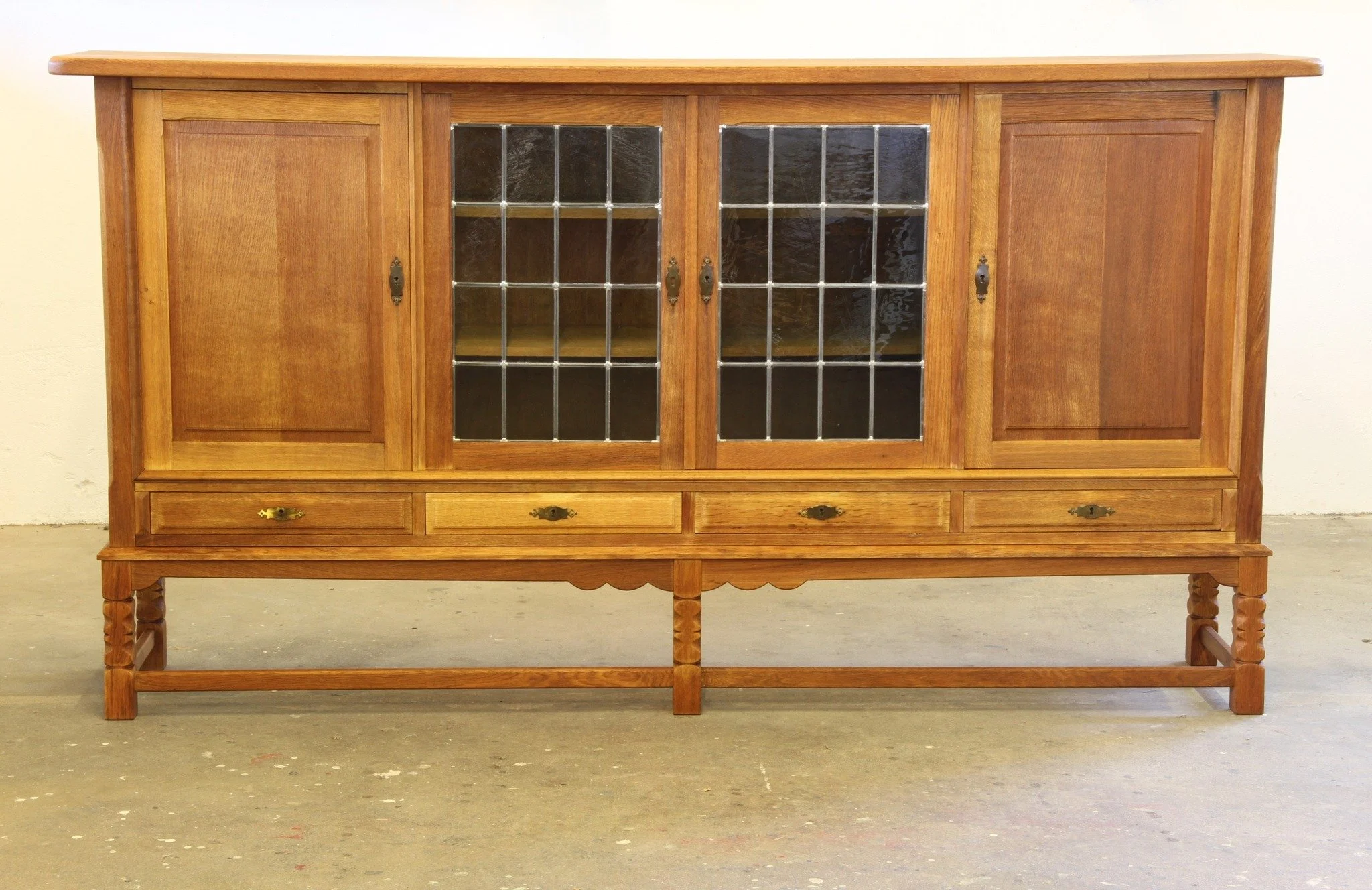 Vintage Danish 1960s Modern Oak Cabinet in the style of Henning Kj&aelig;rnulf 

SKU: mb00058

Big presence. Slim footprint. This stunning 215 cm wide Nordic oak cabinet is a masterclass in Danish design &mdash; five carved legs, glass doors, brass d