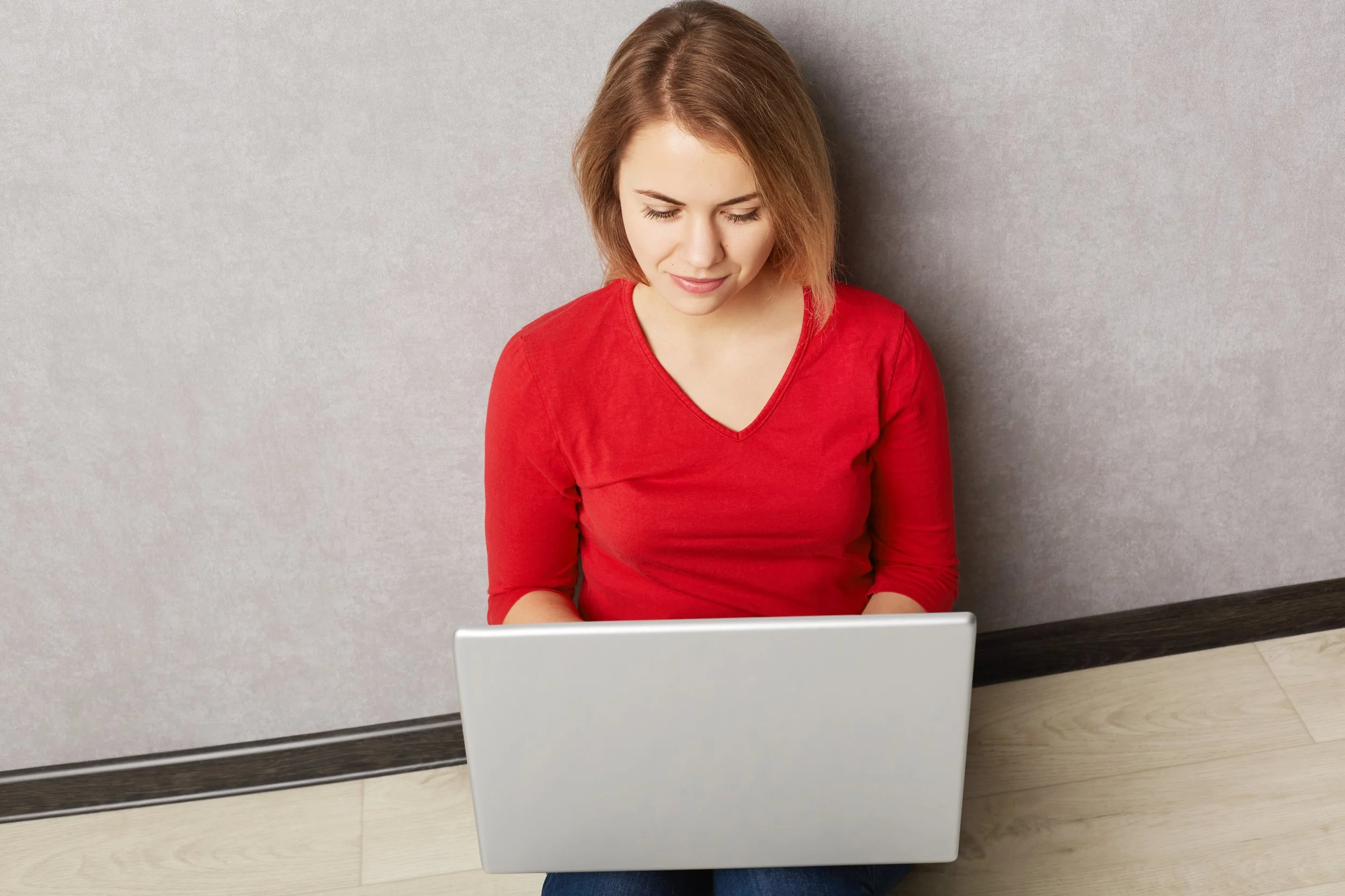 A woman on her laptop and sitting on the ground