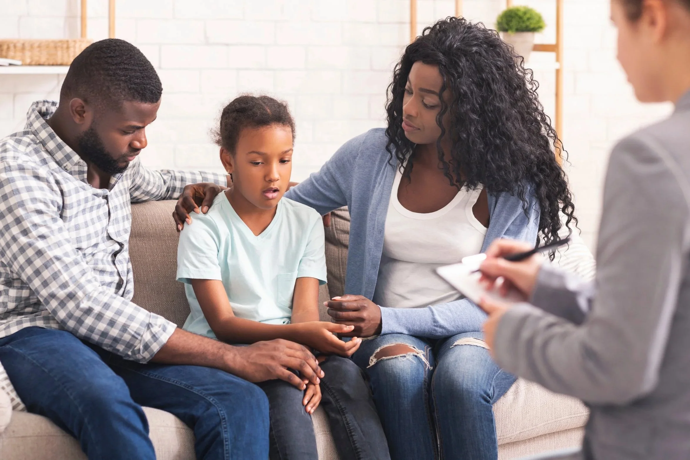 Mother and father on a couch with their 9 year older daughter talking with a therapist.