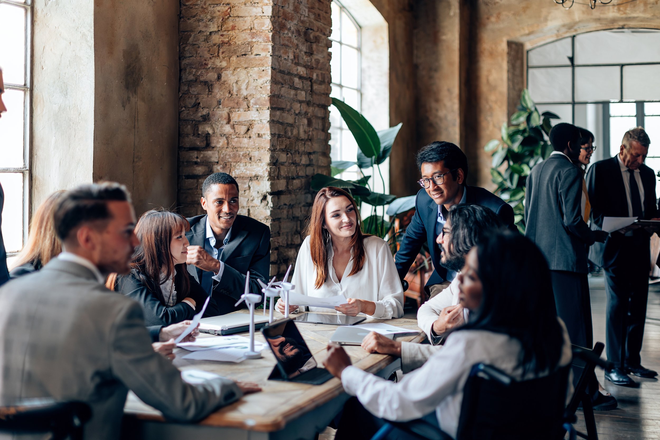 A circle of professionals sitting around a conference table smiling and working on a group project illustrating team work.