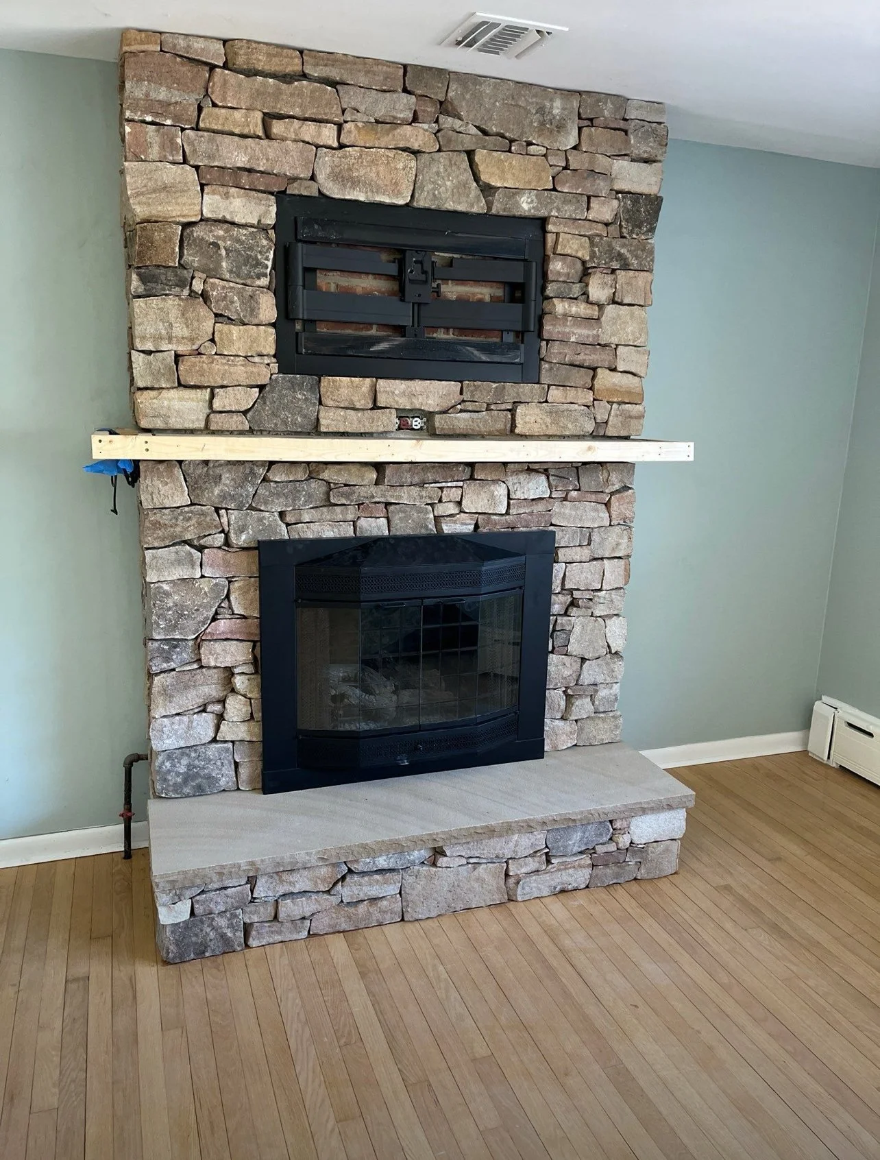 Natural stone fireplace in a Little Silver, NJ home featuring a stacked stone surround and a raised stone hearth.