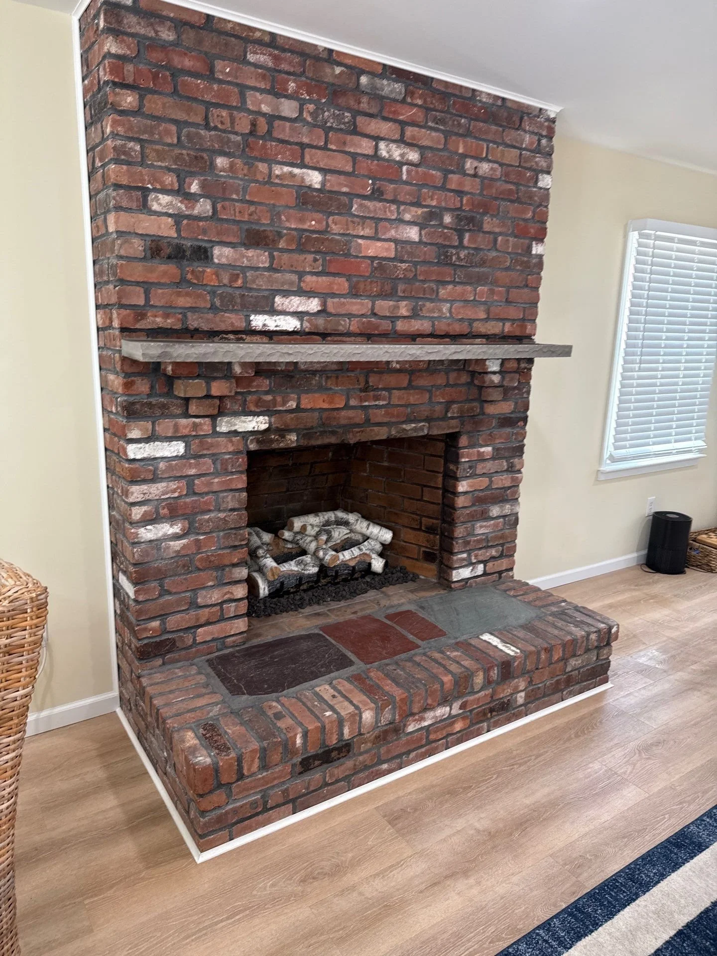 Floor-to-ceiling red brick fireplace with a stone mantel and raised brick hearth in a living room at a Rumson, NJ home.