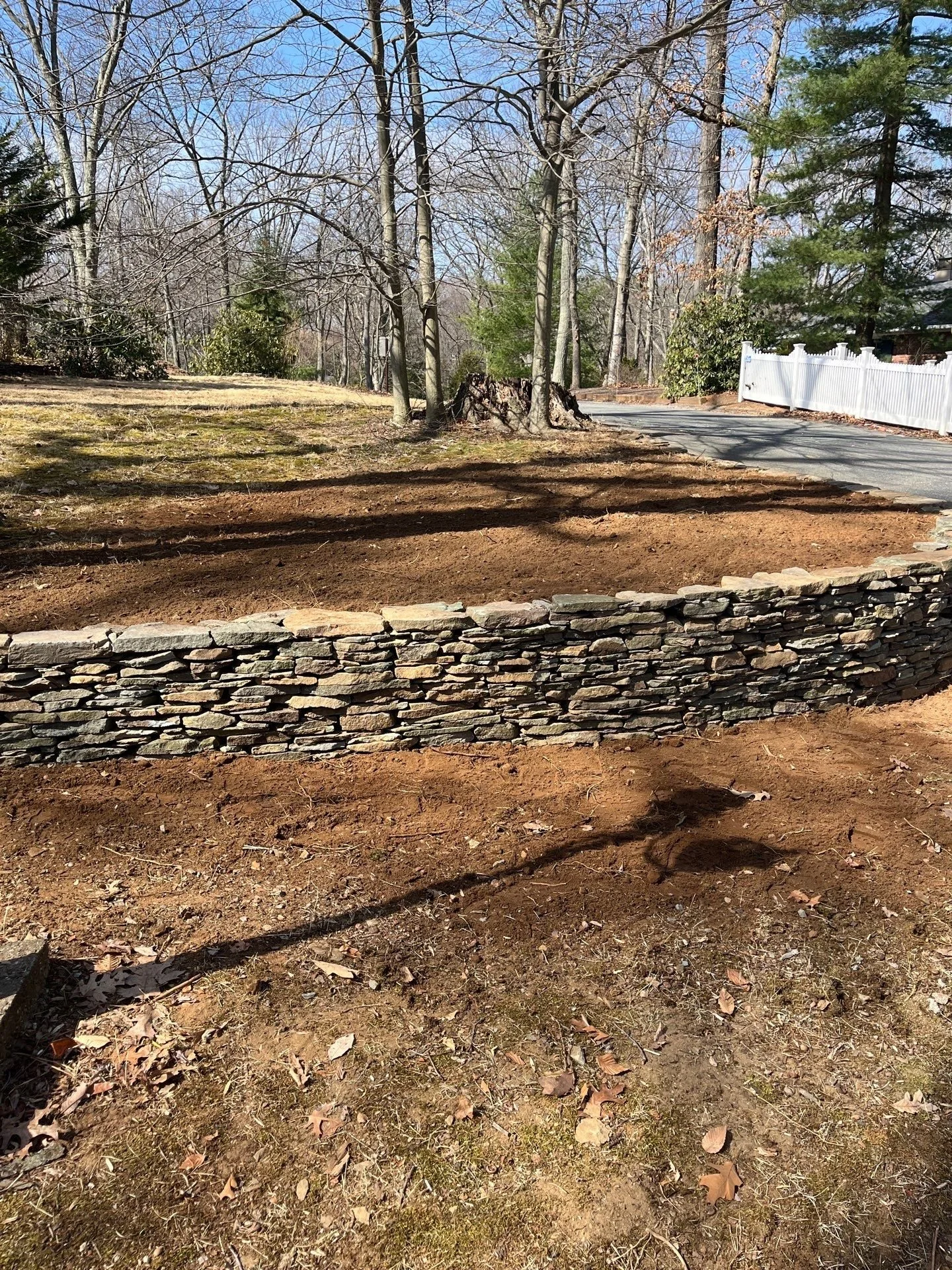 Dry stack stone retaining wall installation in Monmouth County NJ providing natural landscape support and durable outdoor masonry construction.