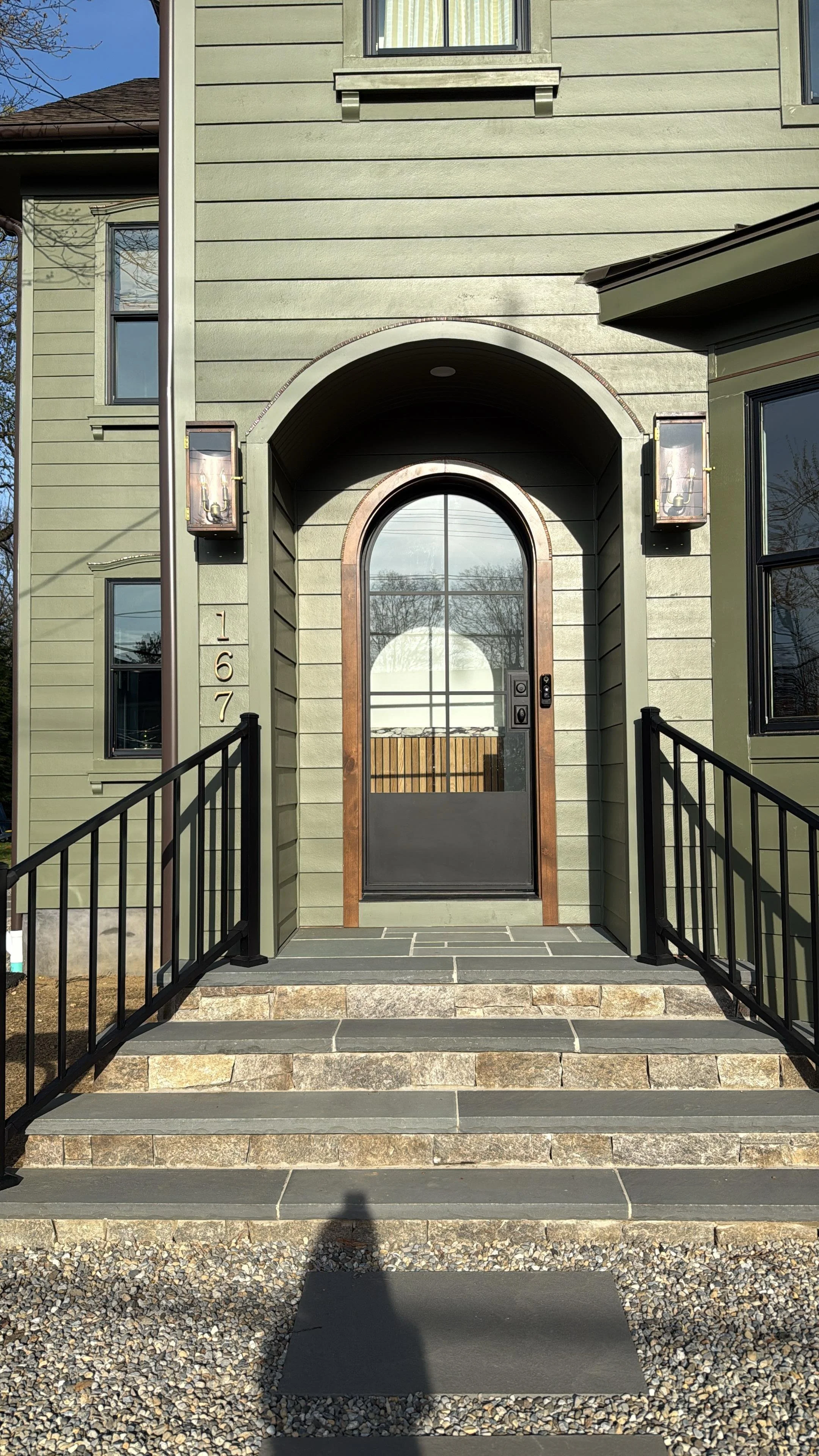 Natural stone entry steps with black metal railings leading to an arched front door at a Middletown, NJ home.