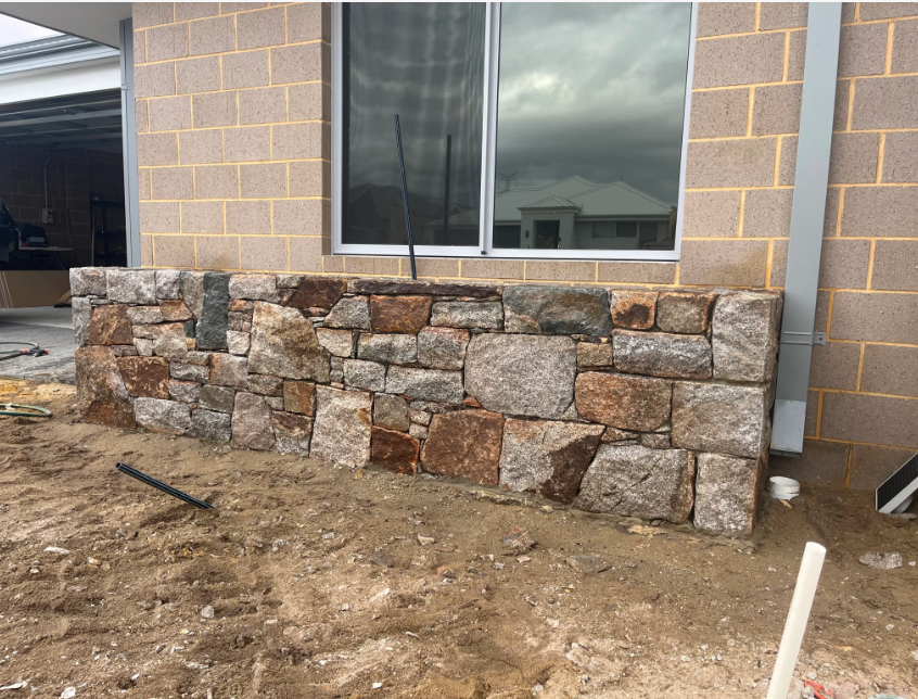 Stone retaining wall beneath a window in a construction area