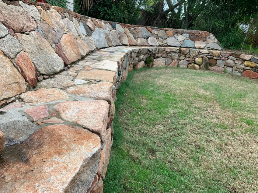 Stone retaining wall with built-in seating in a grassy yard