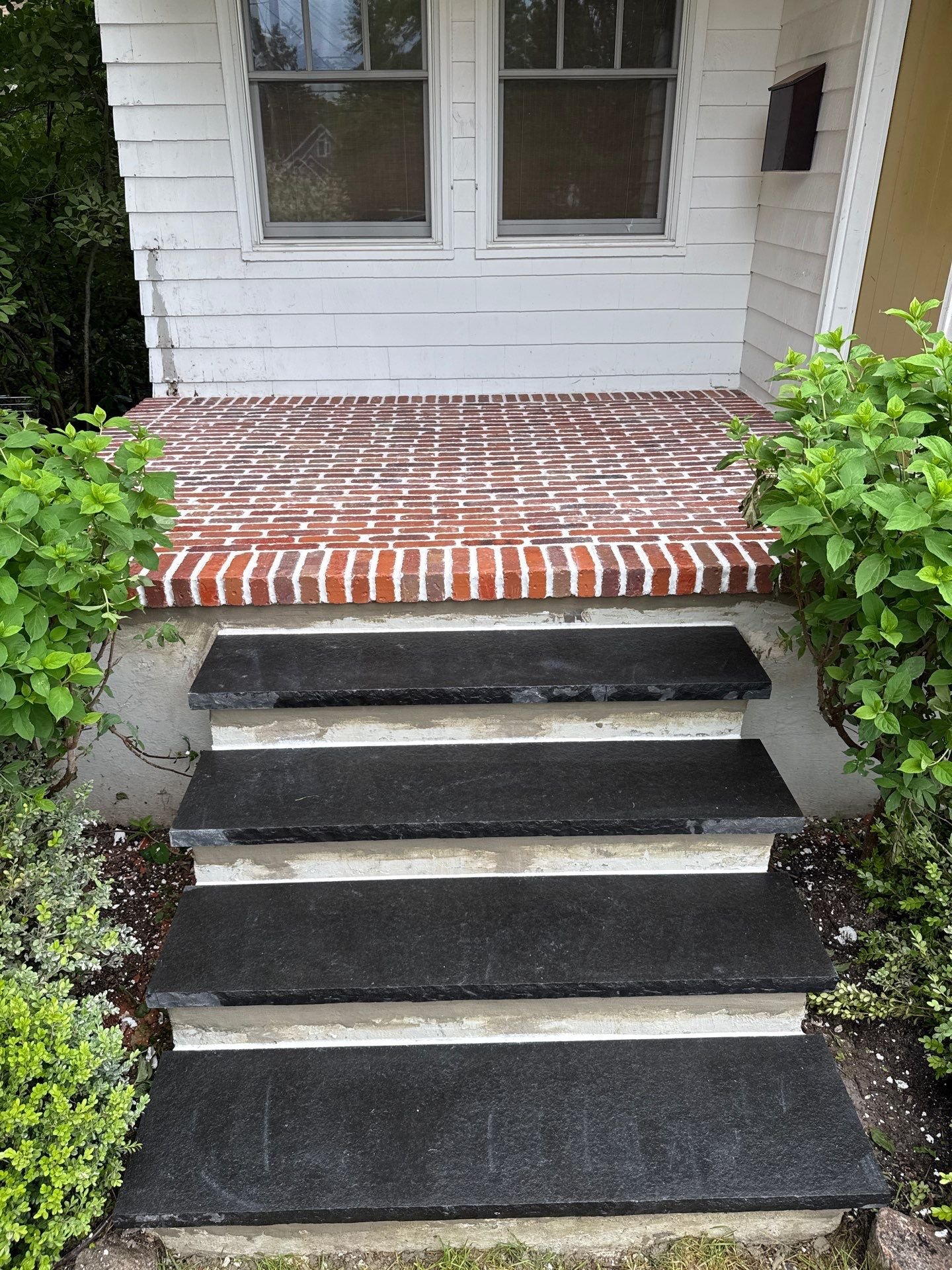 Brick porch and stone step installation in Monmouth County NJ featuring clean masonry work, durable stone treads, and refined front entrance design.