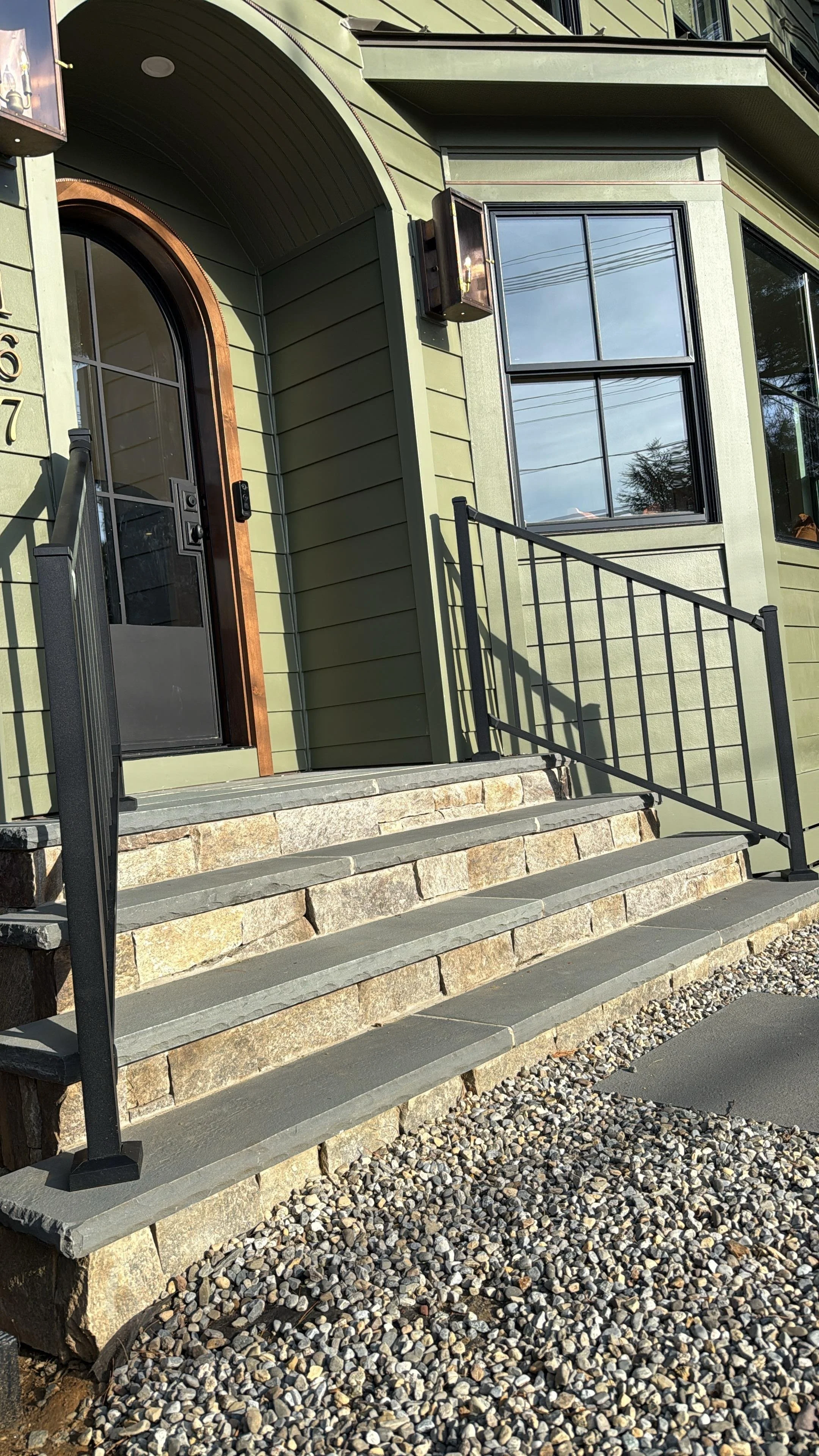 Stone front steps at an Atlantic Highlands, NJ home featuring bluestone treads, a stacked stone riser face, and black metal railings.