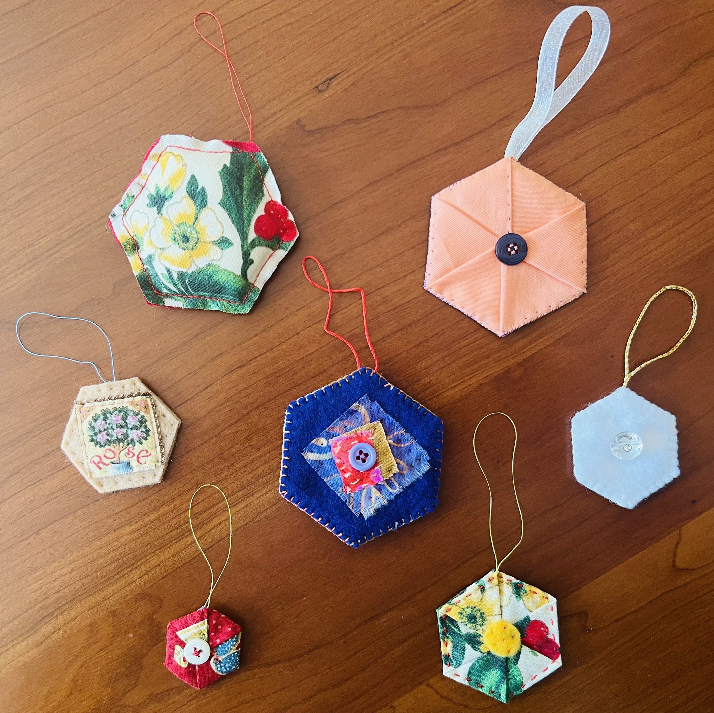 Festive fabric ornaments in various shapes with buttons and ribbons, arranged on a wooden surface.