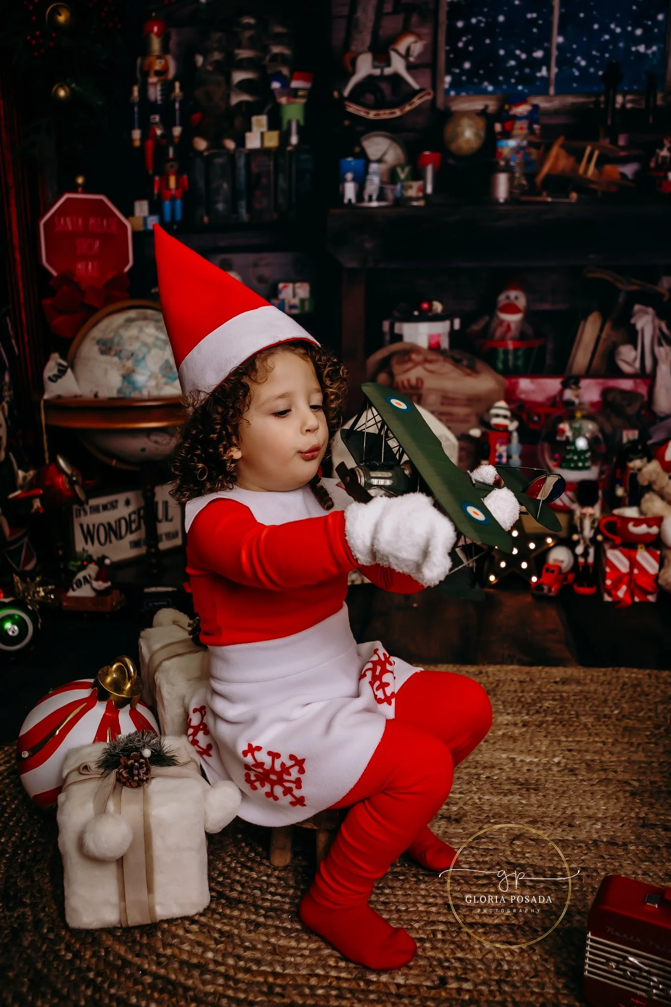A child wearing an elf outfit looking at an airplane.
