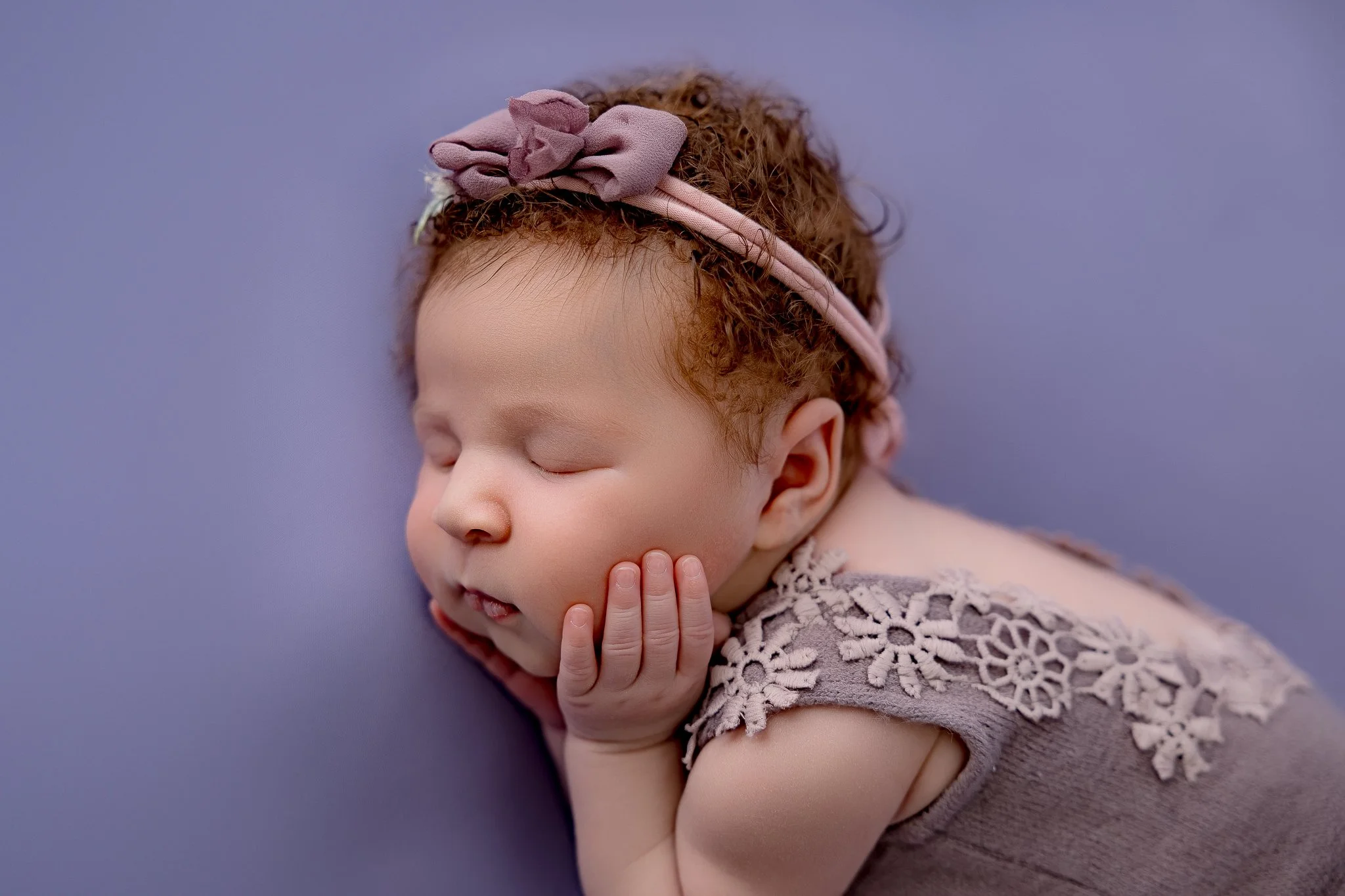 A baby wrapped in a purple wrap in a heart bowl.