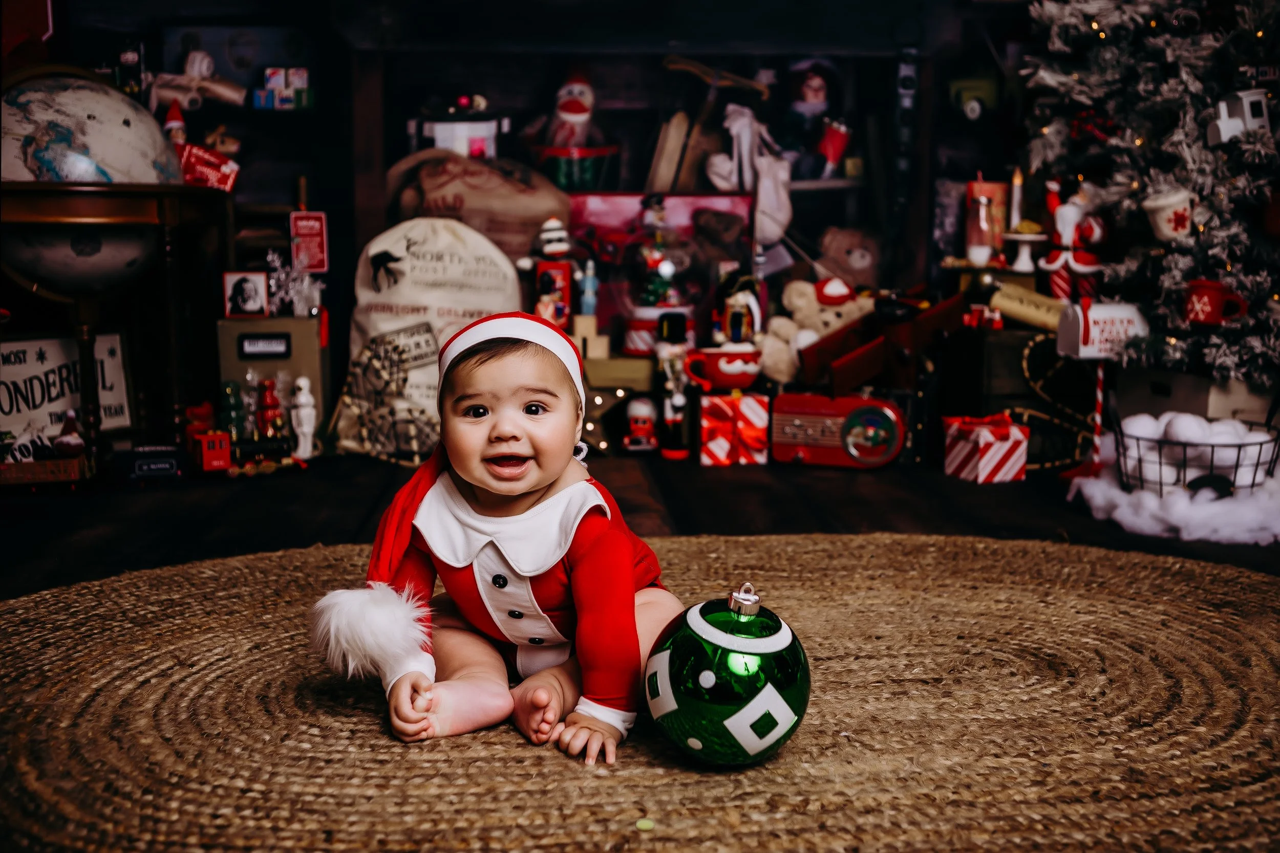 A baby wearing a Santa outfit smiling.