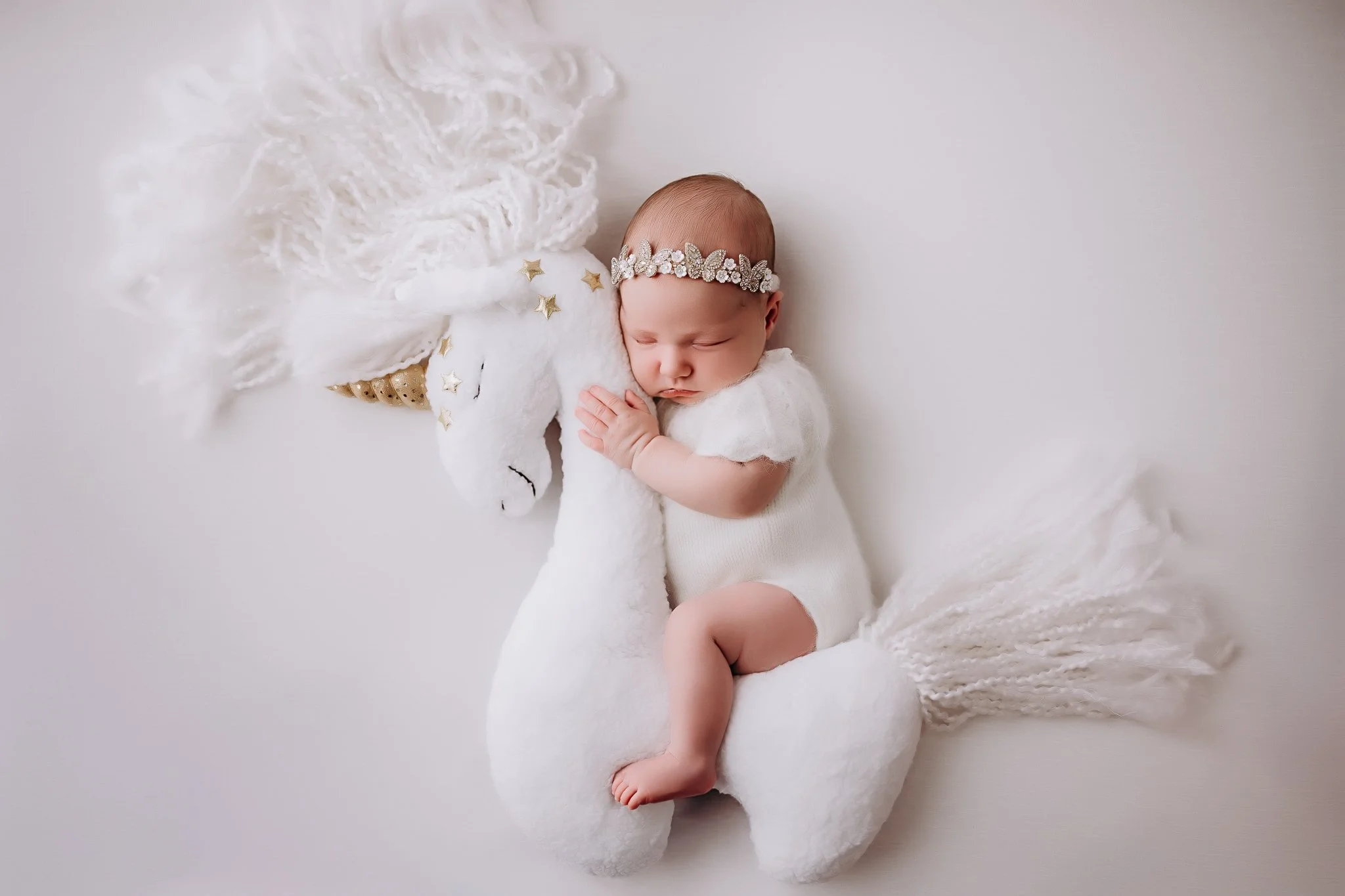 A sleeping baby wearing white with a unicorn.
