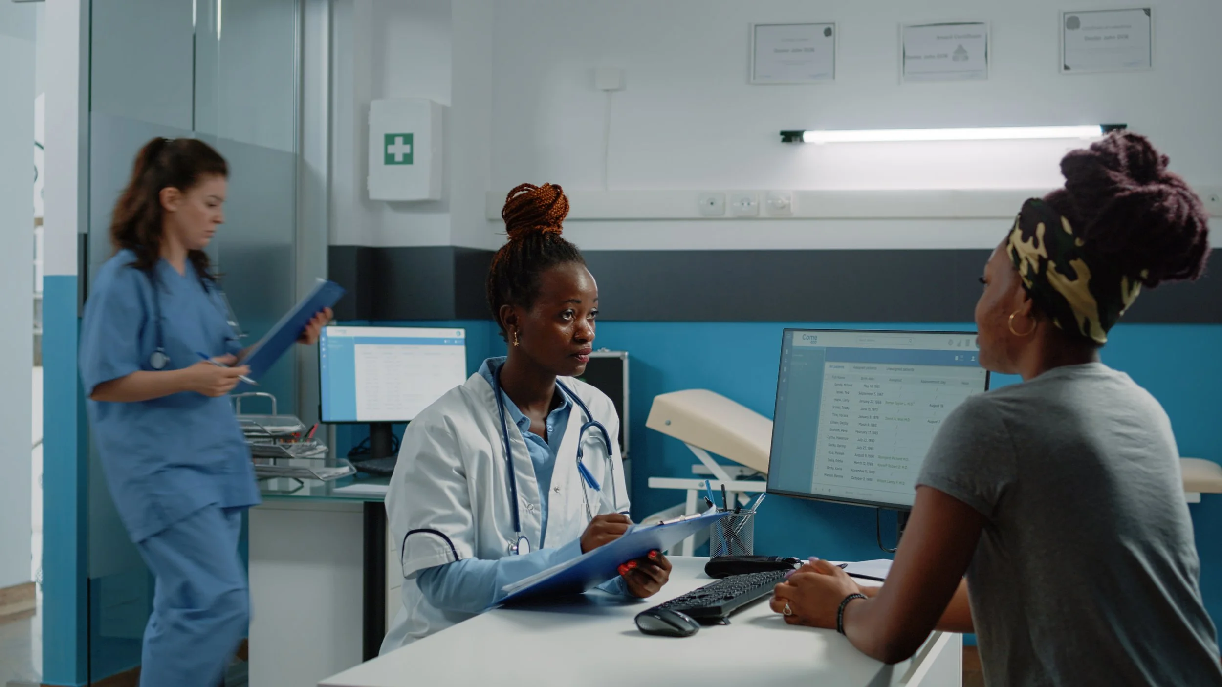 A healthcare professional and a woman in a medical facility, with another nurse in the background.