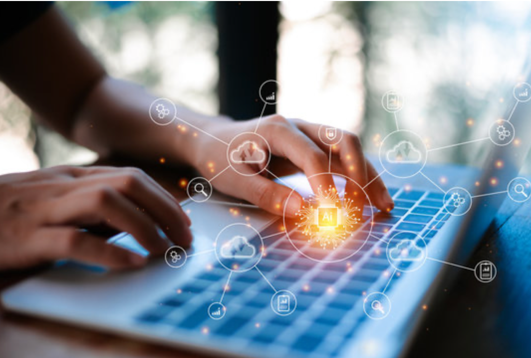 Close-up of hands typing on a laptop keyboard with digital icons and a glowing AI symbol in the foreground.
