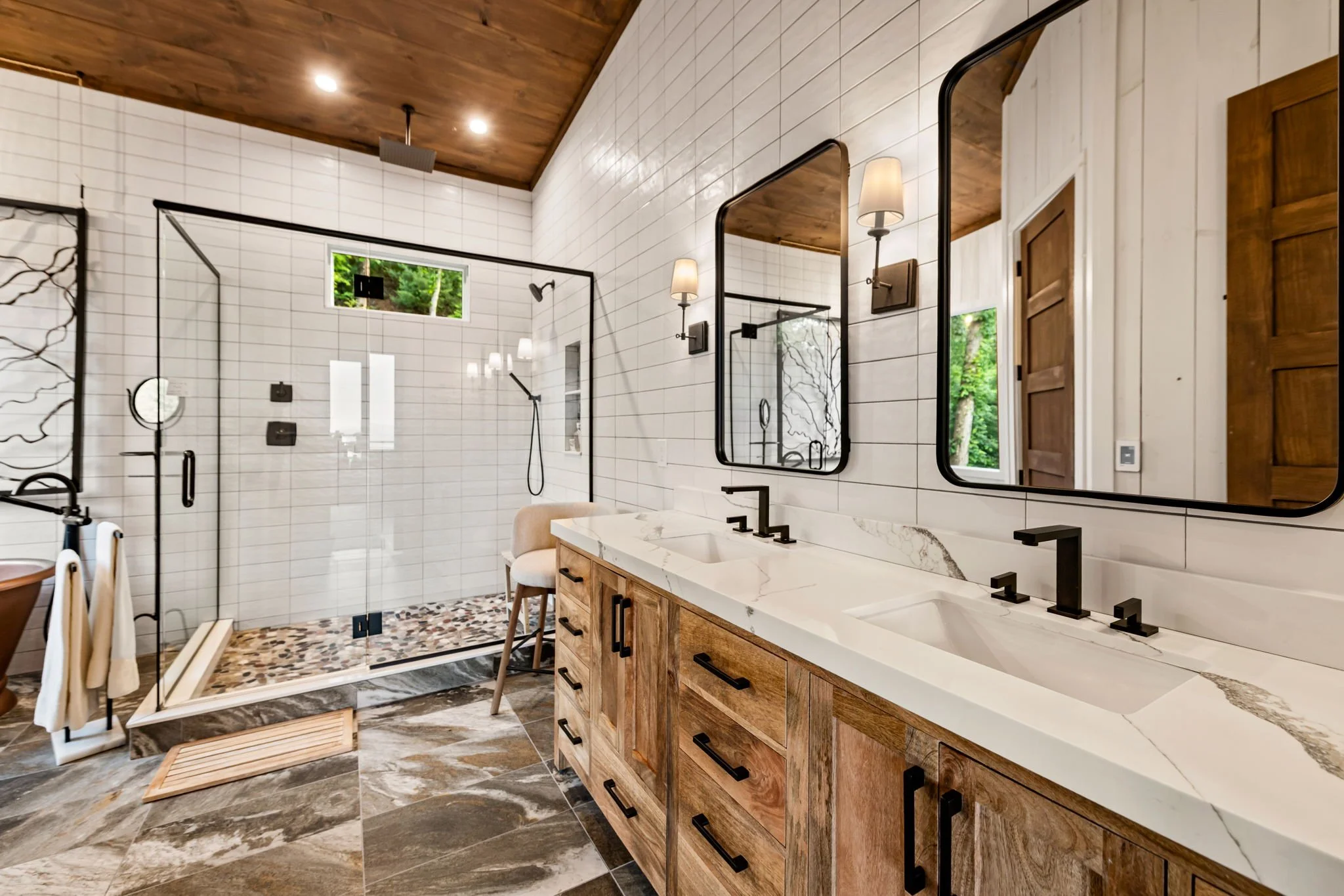 Refresh in this spa-inspired bathroom featuring a double vanity, oversized mirrors, quartz countertops, glass walk-in shower w/ rainfall head, designer lighting, & luxury finishes—creating a bright, modern space for relaxing & getting ready in style.
