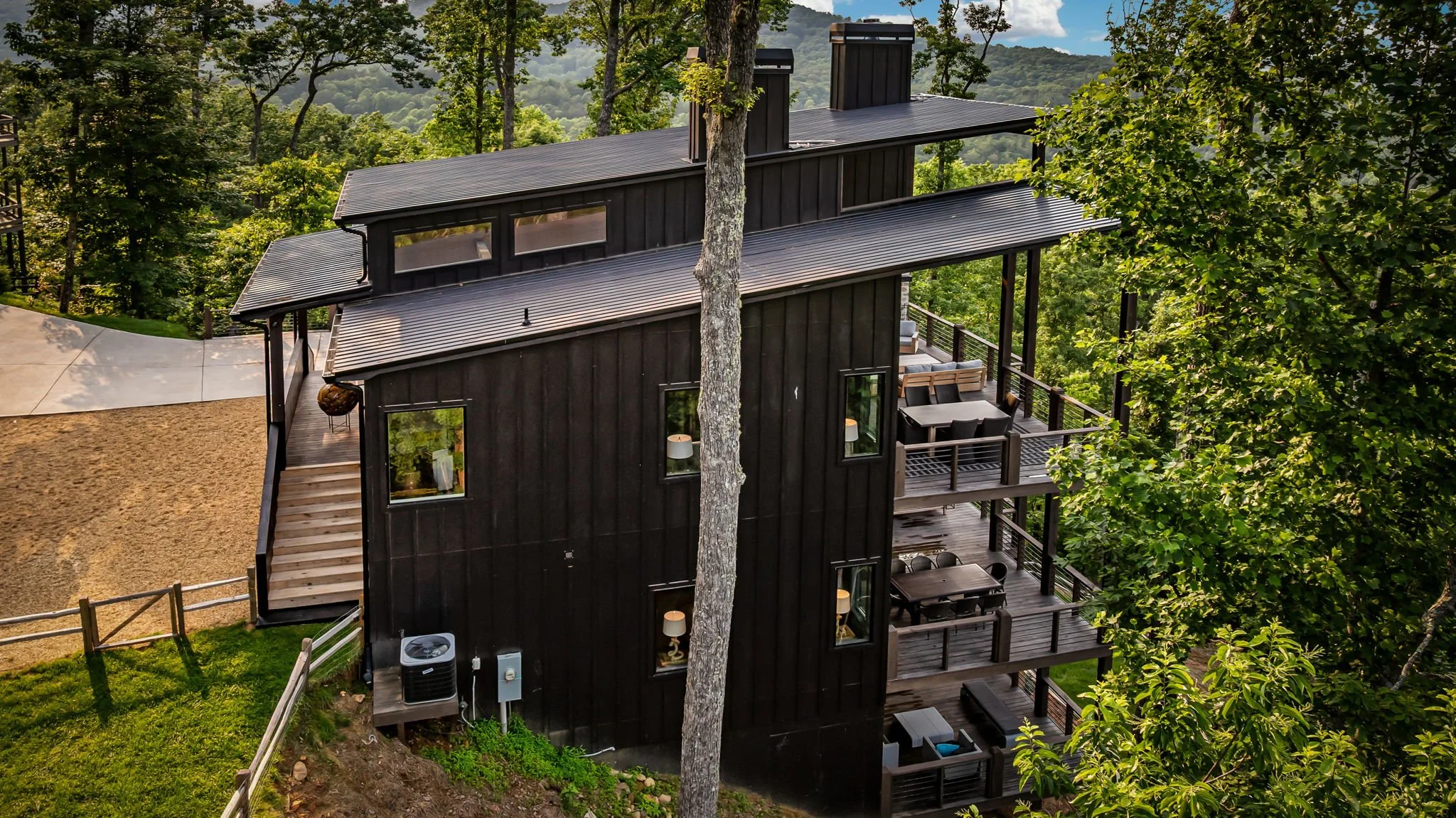 Discover this striking modern mountain home featuring multiple covered decks, outdoor lounge spaces, sleek architectural design, forest surroundings, and scenic mountain views—a luxurious private retreat perfect for relaxing, entertainment and more.