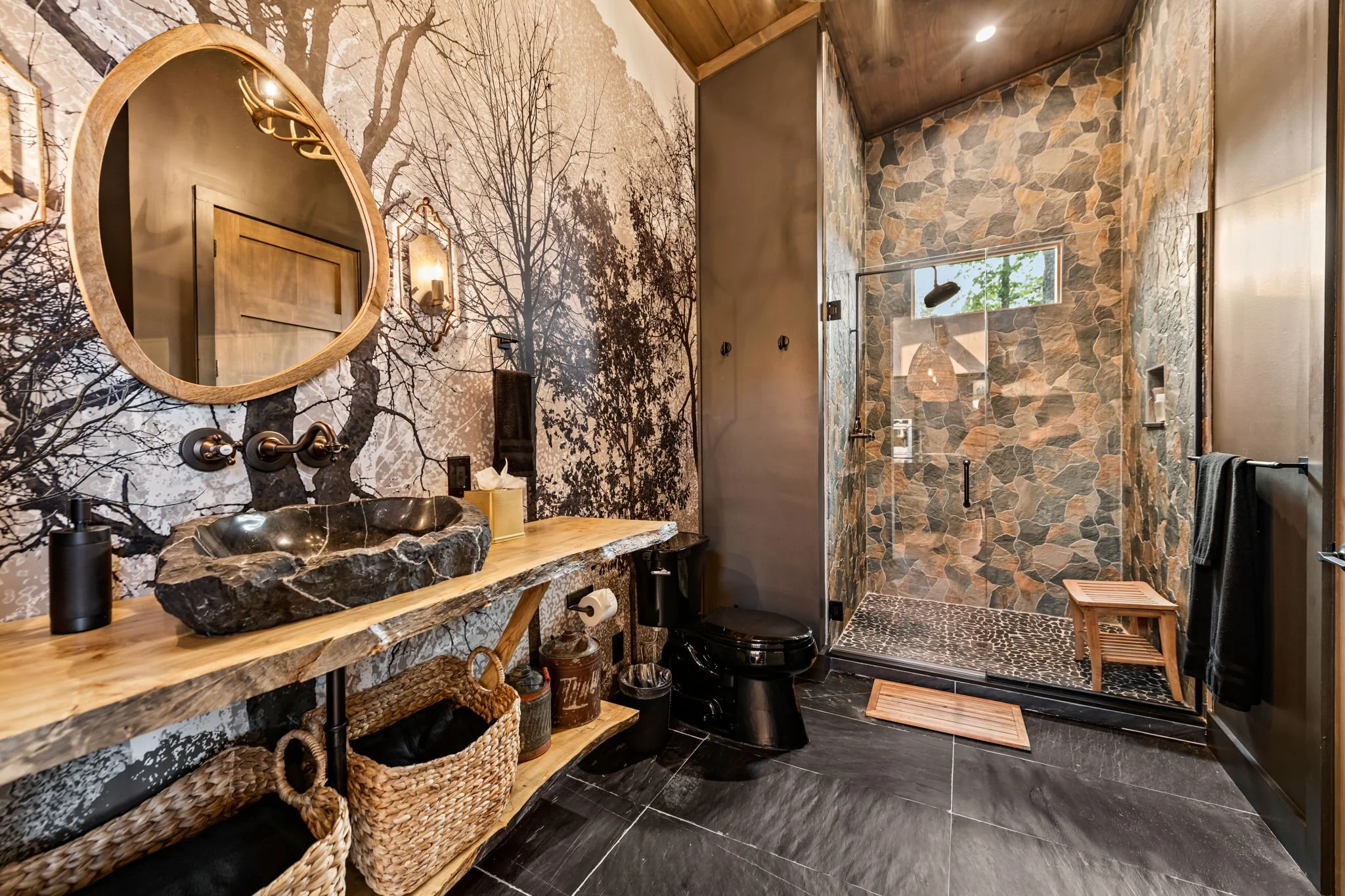 Indulge in this spa-inspired bathroom with a stone vessel sink, live-edge vanity, designer wallpaper, and a spacious glass walk-in shower with natural stone tile. Thoughtfully curated finishes create a refined, luxurious retreat.