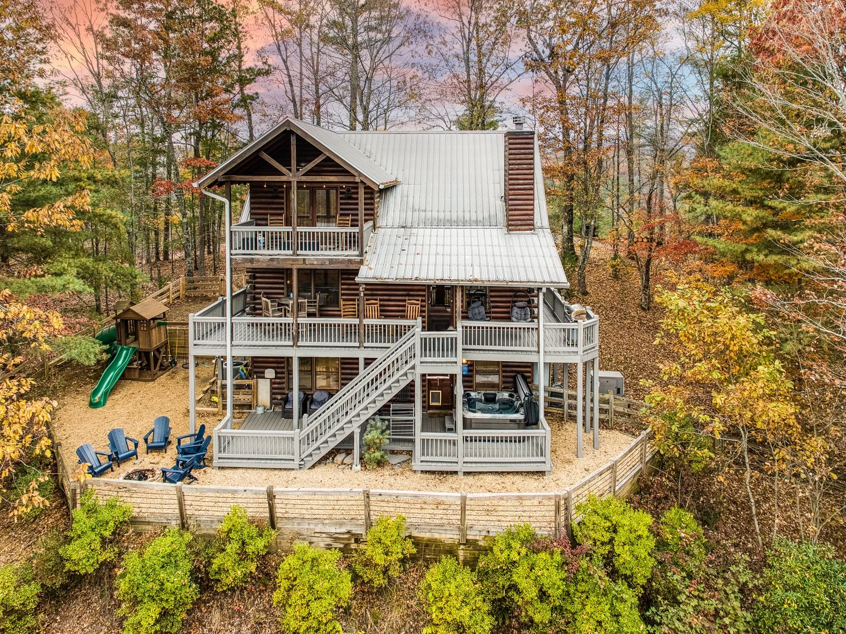 An amazing view of your private outdoor oasis with a fire pit, jacuzzi, playground, and fully fenced yard - surrounded by breathtaking mountain views, vibrant fall colors, and peaceful forest scenery for the perfect secluded North Georgia escape.”