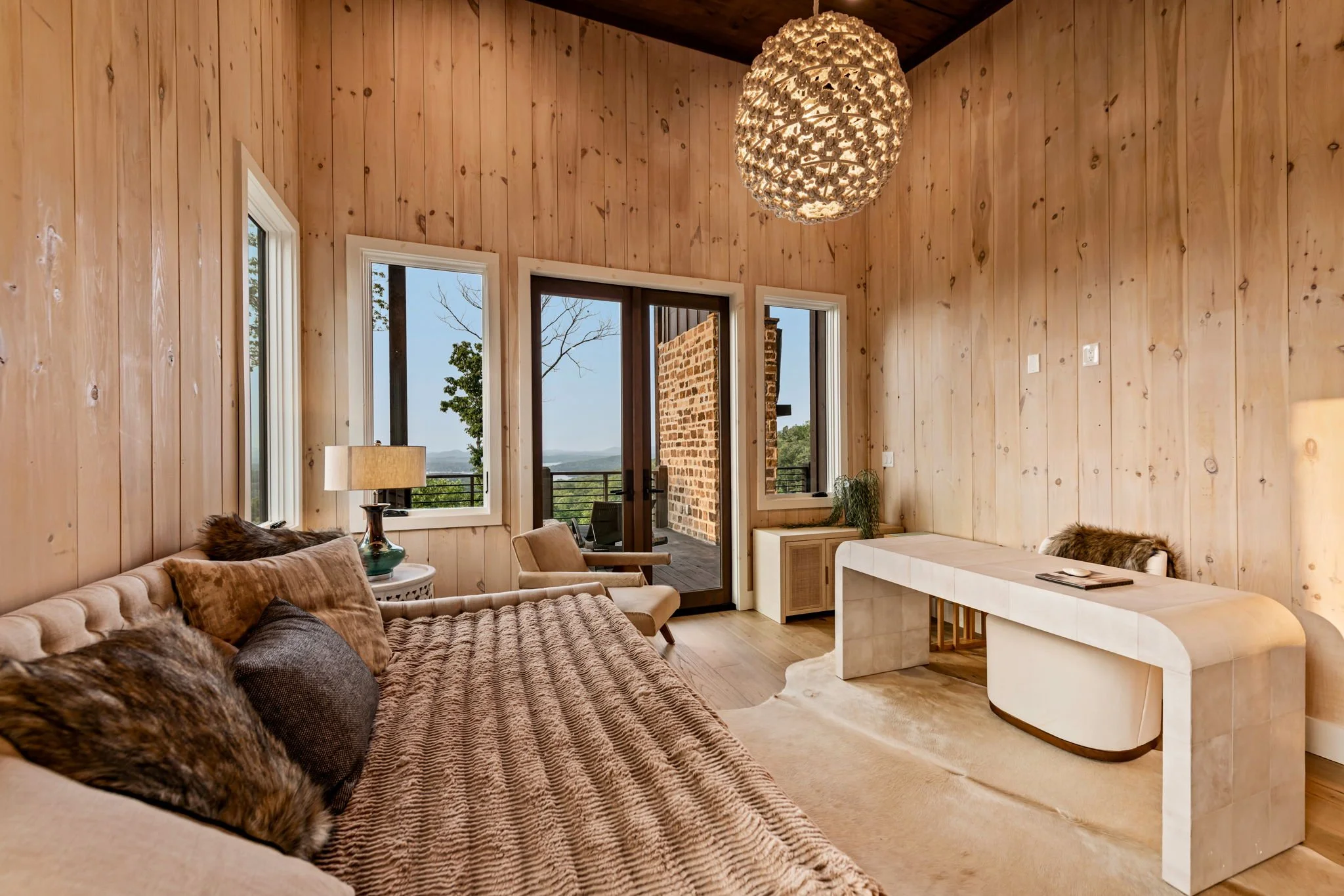 Unwind in Bedroom 2, an elegant lounge-style suite with plush seating, designer lighting, & warm wood interiors. Large windows & terrace access showcase sweeping mountain & lake views, creating a serene space for quiet mornings or evening relaxation.