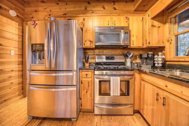 The fully stocked kitchen features stainless steel appliances, a four-burner gas stove, toaster, crockpots, blender, and all essentials needed to cook for a large family. Perfect for preparing holiday meals, group dinners, and cozy cabin gatherings.