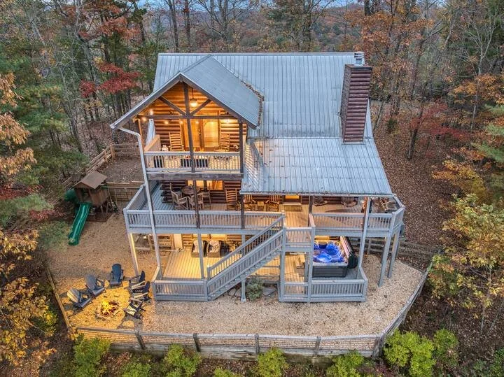 Check out this bird’s-eye view of the private outdoor oasis featuring a fire-pit, jacuzzi, playground, and a fully fenced-in yard with a wraparound porch - perfect for family-friendly and pet-friendly fun in a secluded North Georgia mountain setting.