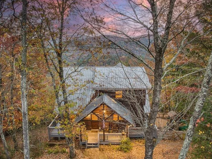 Cherry Log Summit - the front porch showcases a warm, inviting entrance surrounded by vibrant fall colors & mountain scenery. Perched atop a secluded hilltop, you’ll arrive to breathtaking views and a cozy North Georgia retreat tucked into the trees!