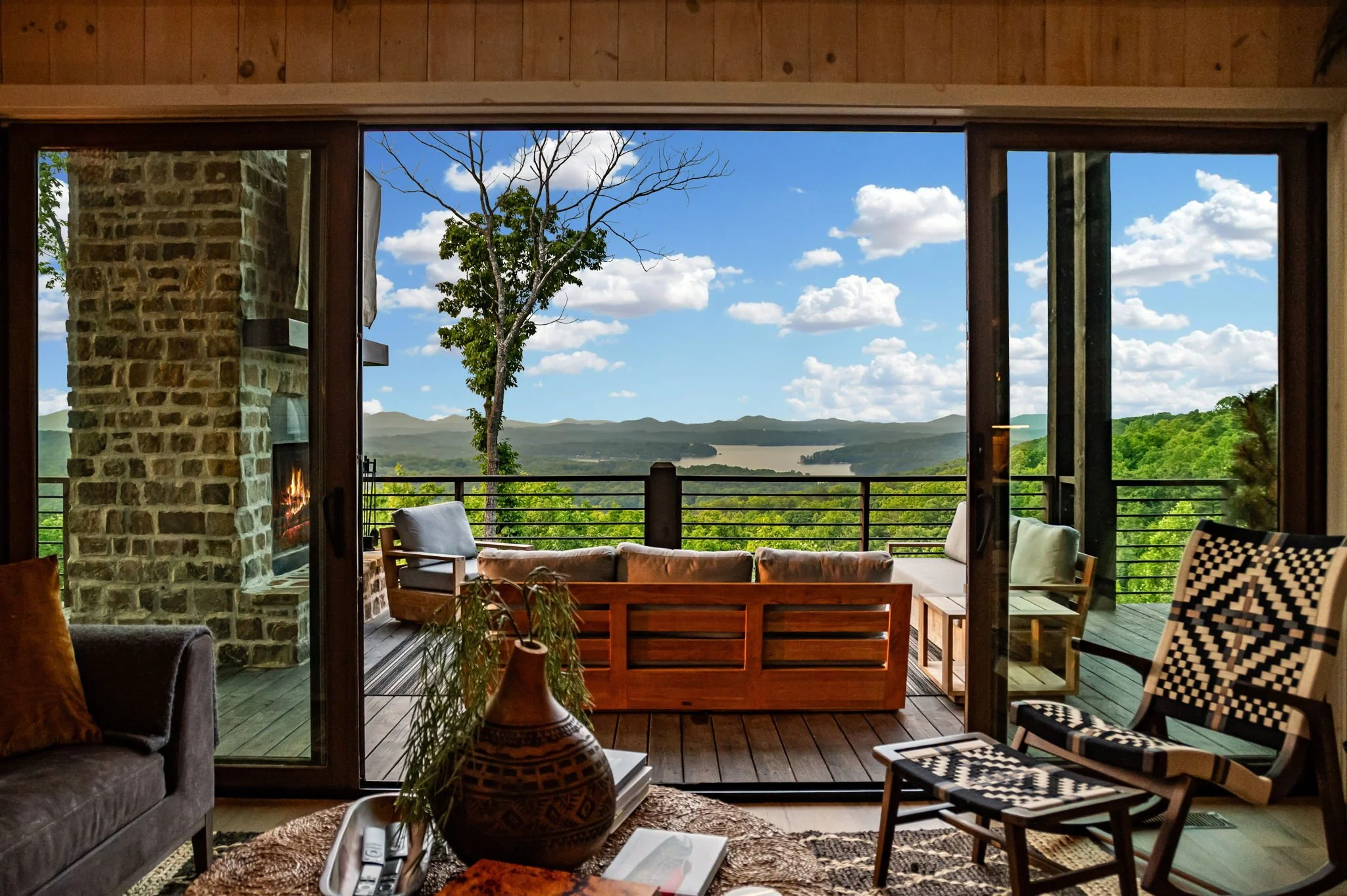 Relax as floor-to-ceiling doors open to an expansive terrace with sweeping mountain and lake views. Elegant indoor-outdoor living, refined seating, and a stone fireplace create the perfect setting for elevated mountain retreat moments.