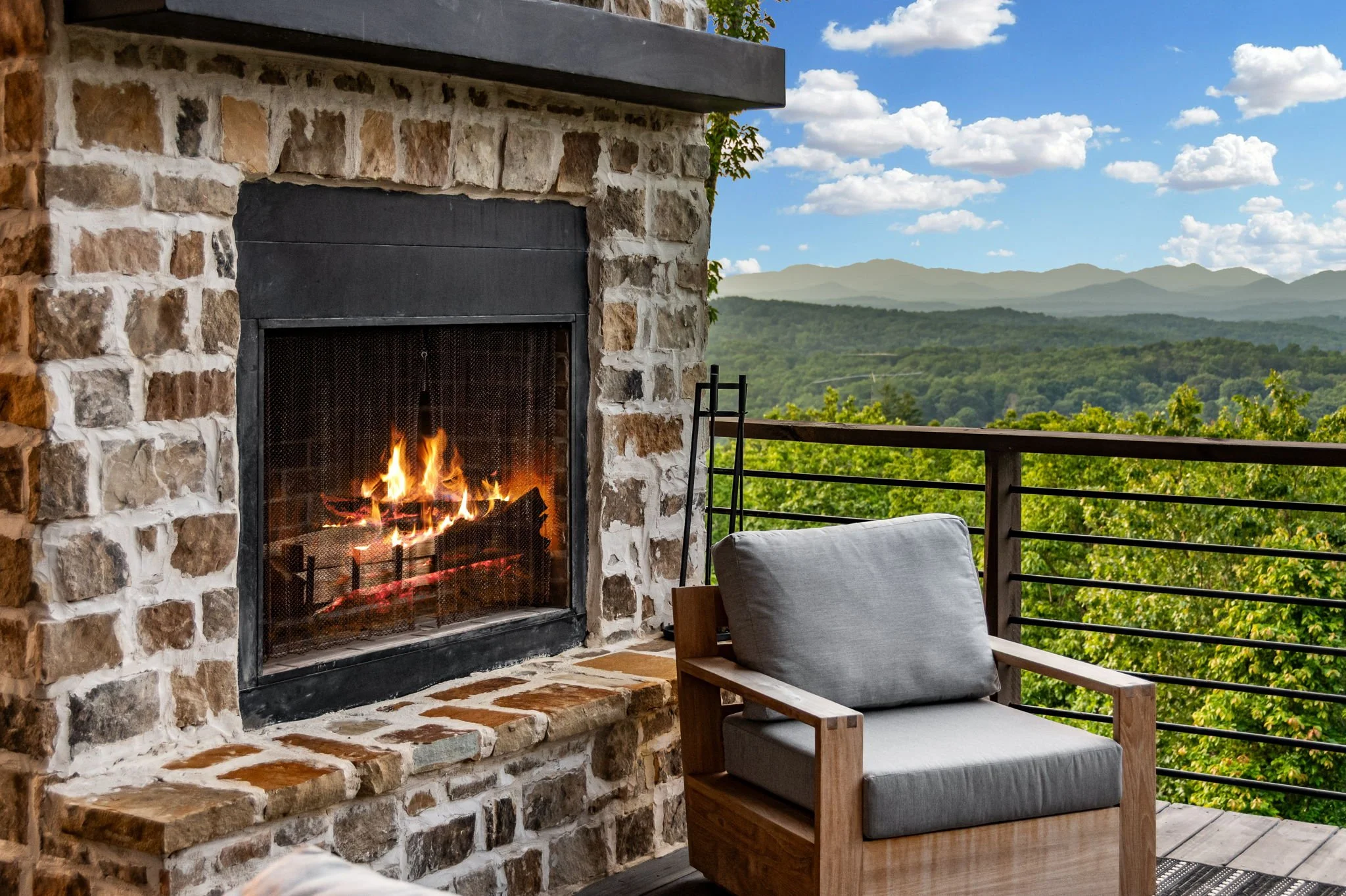 Cozy up by the outdoor stone fireplace while enjoying comfortable lounge seating and breathtaking mountain & lake views—a perfect luxury spot for relaxing mornings or peaceful evenings surrounded by nature.