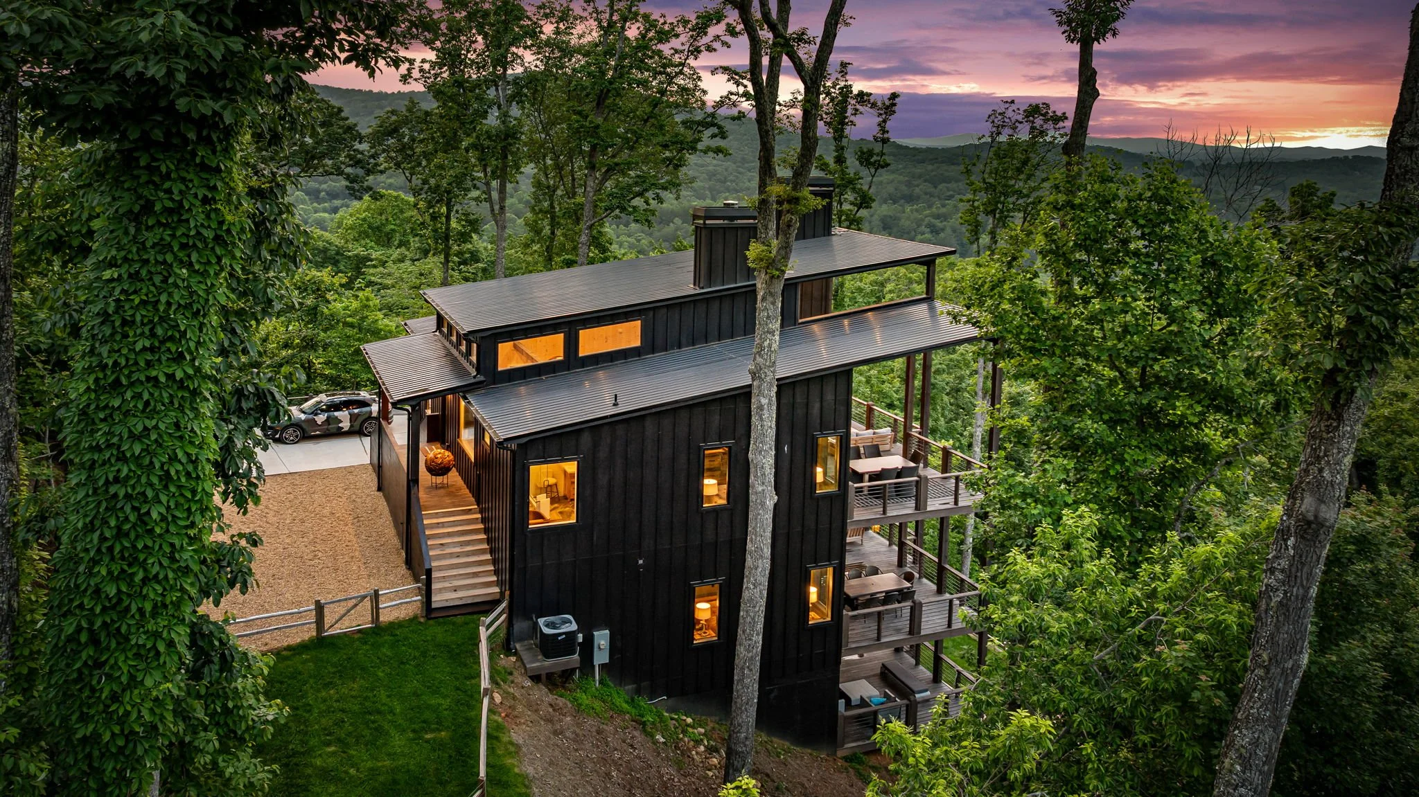 Discover this striking modern mountain home featuring multiple covered decks, outdoor lounge spaces, sleek architectural design, forest surroundings, and scenic mountain views—a luxurious private retreat perfect for relaxing, entertainment and more.
