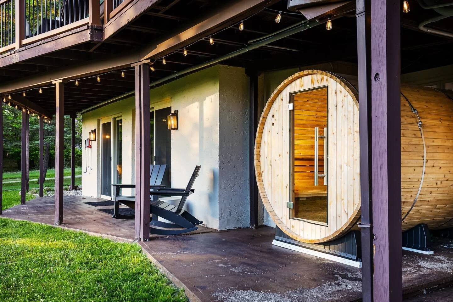 The back patio features a covered 7-person jacuzzi + 6-person barrel sauna, both tucked under the deck. String lights add ambiance, while both offer stunning sunset views over the valley, they’re perfect after a long day of ski or golf at the resort!