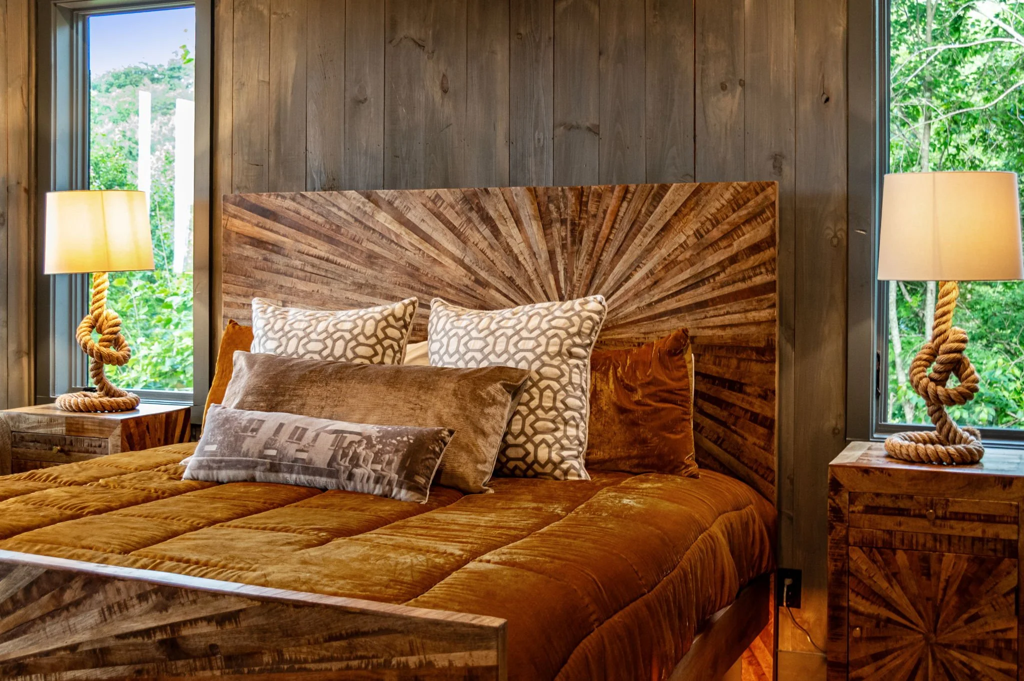 Rest peacefully in Bedroom 4 featuring a beautifully crafted wood statement bed, plush bedding, designer lighting, and large windows bringing in serene forest views—creating a warm, inviting retreat for a restful and luxurious mountain stay.