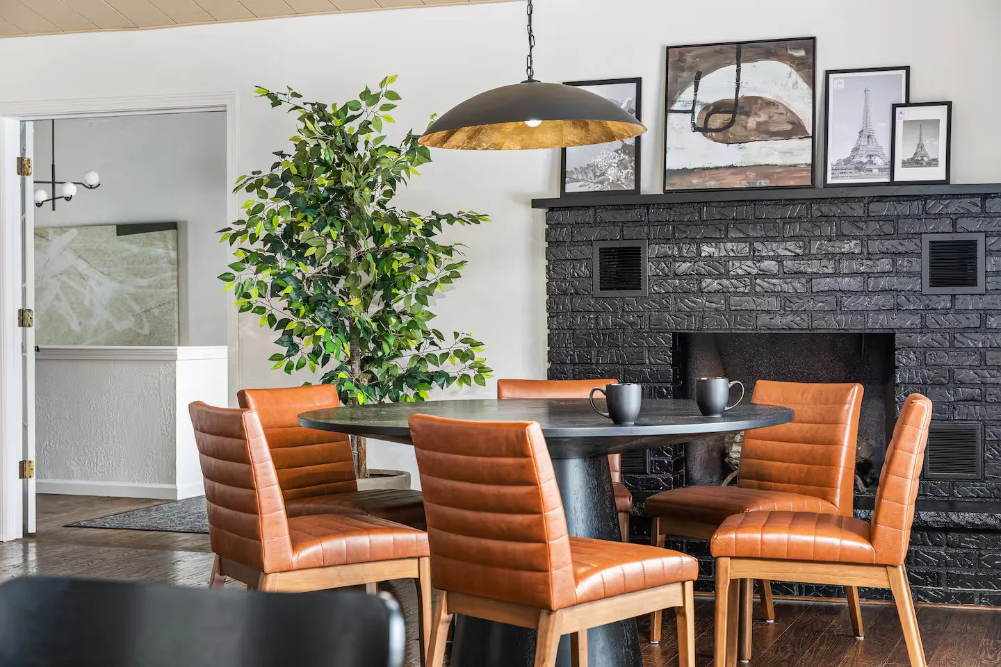 A cozy bistro seating area for 6 near the fireplace, ideal for morning coffees or extra seating during holiday gatherings. The dining room features upscale brown leather chairs & a sleek, round modern table, blending comfort & style for any occasion!