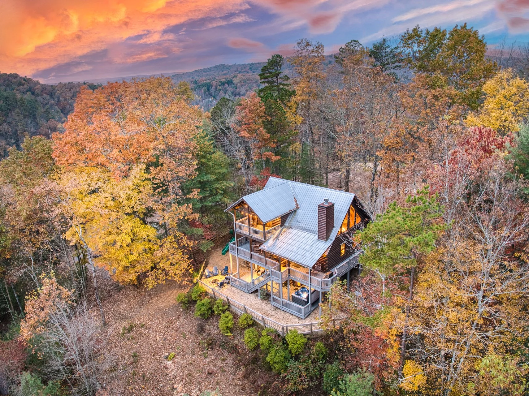 An amazing view of your private outdoor oasis with a fire pit, jacuzzi, playground, and fully fenced yard - surrounded by breathtaking mountain views, vibrant fall colors, and peaceful forest scenery for the perfect secluded North Georgia escape.”