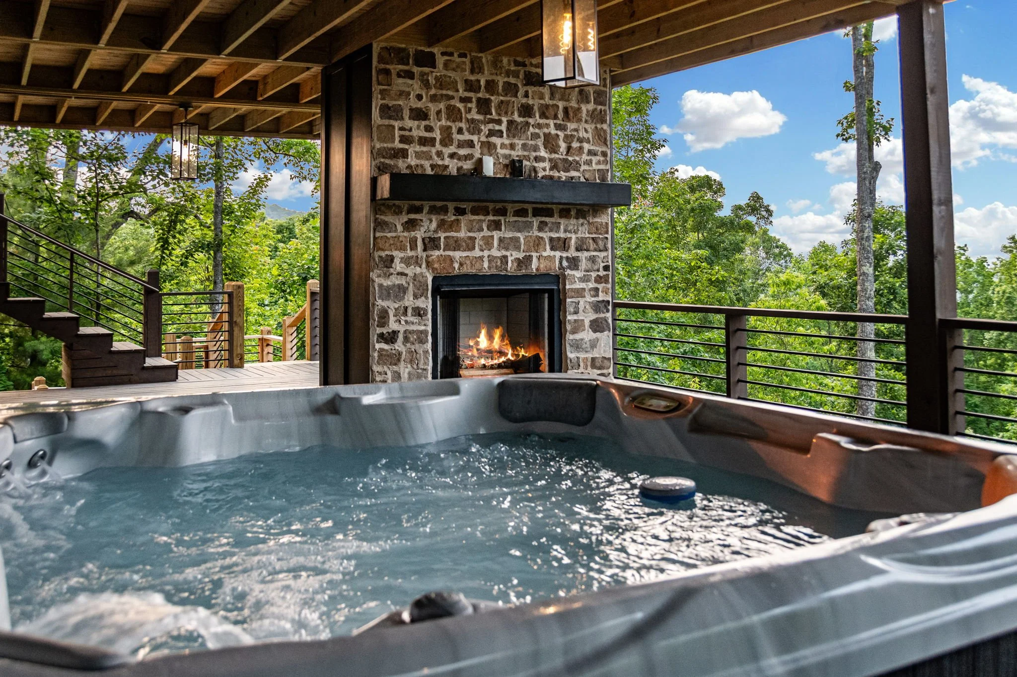 Relax in the private outdoor hot tub while enjoying breathtaking mountain views and a cozy stone fireplace. This covered deck retreat offers the perfect blend of luxury, warmth, and fresh mountain air for unforgettable evenings.