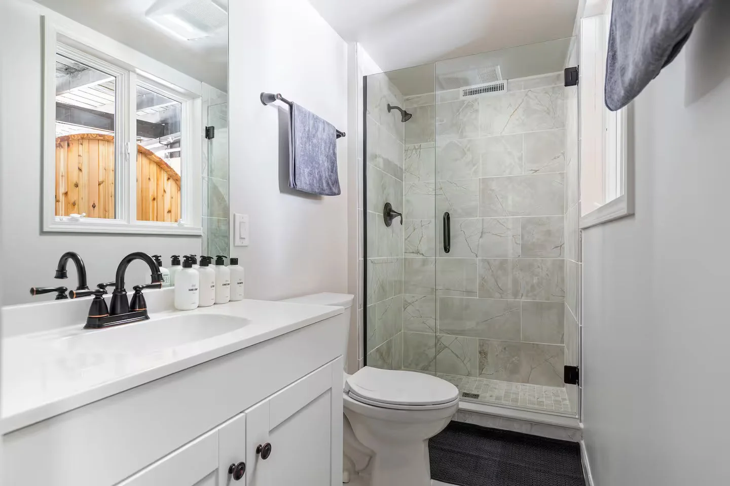 The recently renovated bathroom is connected to Bedroom #2, a queen en-suite downstairs. It features a new tiled & glass shower, along w/ high-quality linens, hair dryer, hand soap, body wash, shampoo, + conditioner for added comfort and convenience.