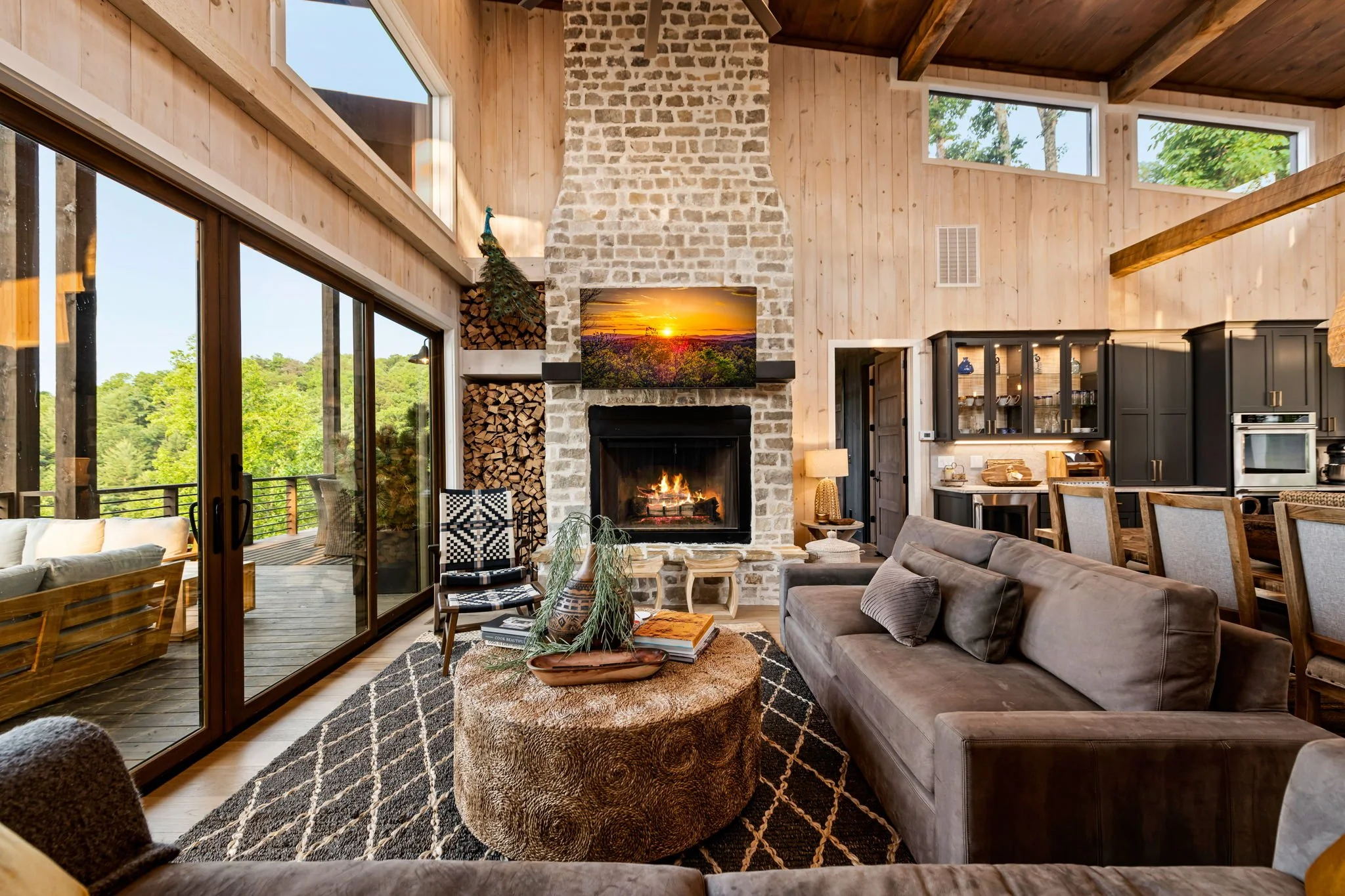 Unwind in the grand living area with soaring ceilings, a striking stone fireplace, and designer furnishings. Expansive glass doors open to the terrace w/ breathtaking mountain & lake views, blending elegant comfort w/ elevated indoor-outdoor living.