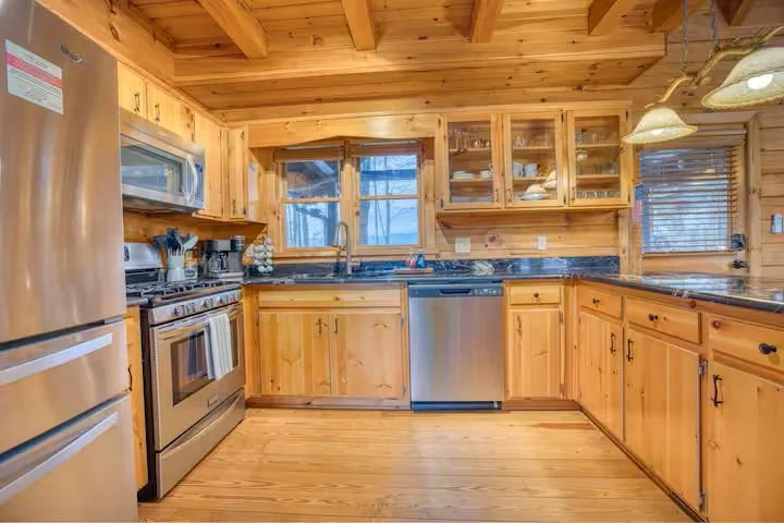 The fully stocked kitchen features stainless steel appliances, a four-burner gas stove, toaster, crockpots, blender, and all essentials needed to cook for a large family. Perfect for preparing holiday meals, group dinners, and cozy cabin gatherings.
