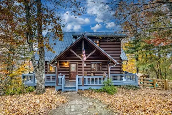 Cherry Log Summit - the front porch showcases a warm, inviting entrance surrounded by vibrant fall colors & mountain scenery. Perched atop a secluded hilltop, you’ll arrive to breathtaking views and a cozy North Georgia retreat tucked into the trees!