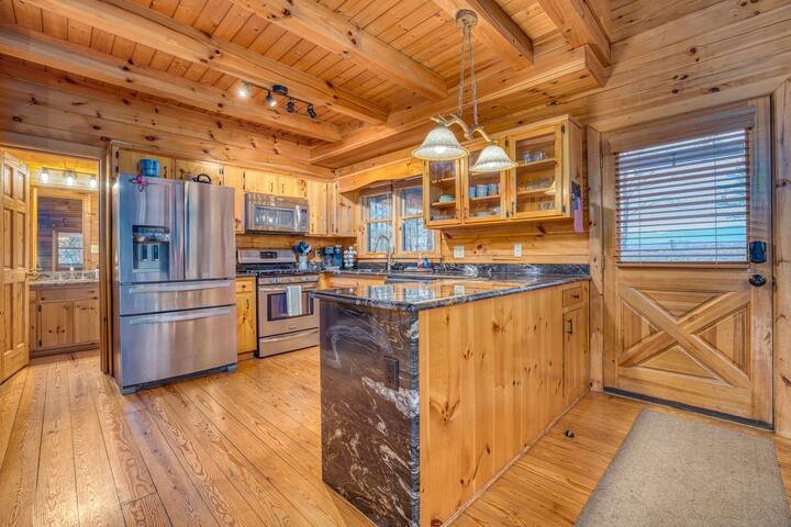The fully stocked kitchen features stainless steel appliances, a four-burner gas stove, toaster, crockpots, blender, and all essentials needed to cook for a large family. Perfect for preparing holiday meals, group dinners, and cozy cabin gatherings.