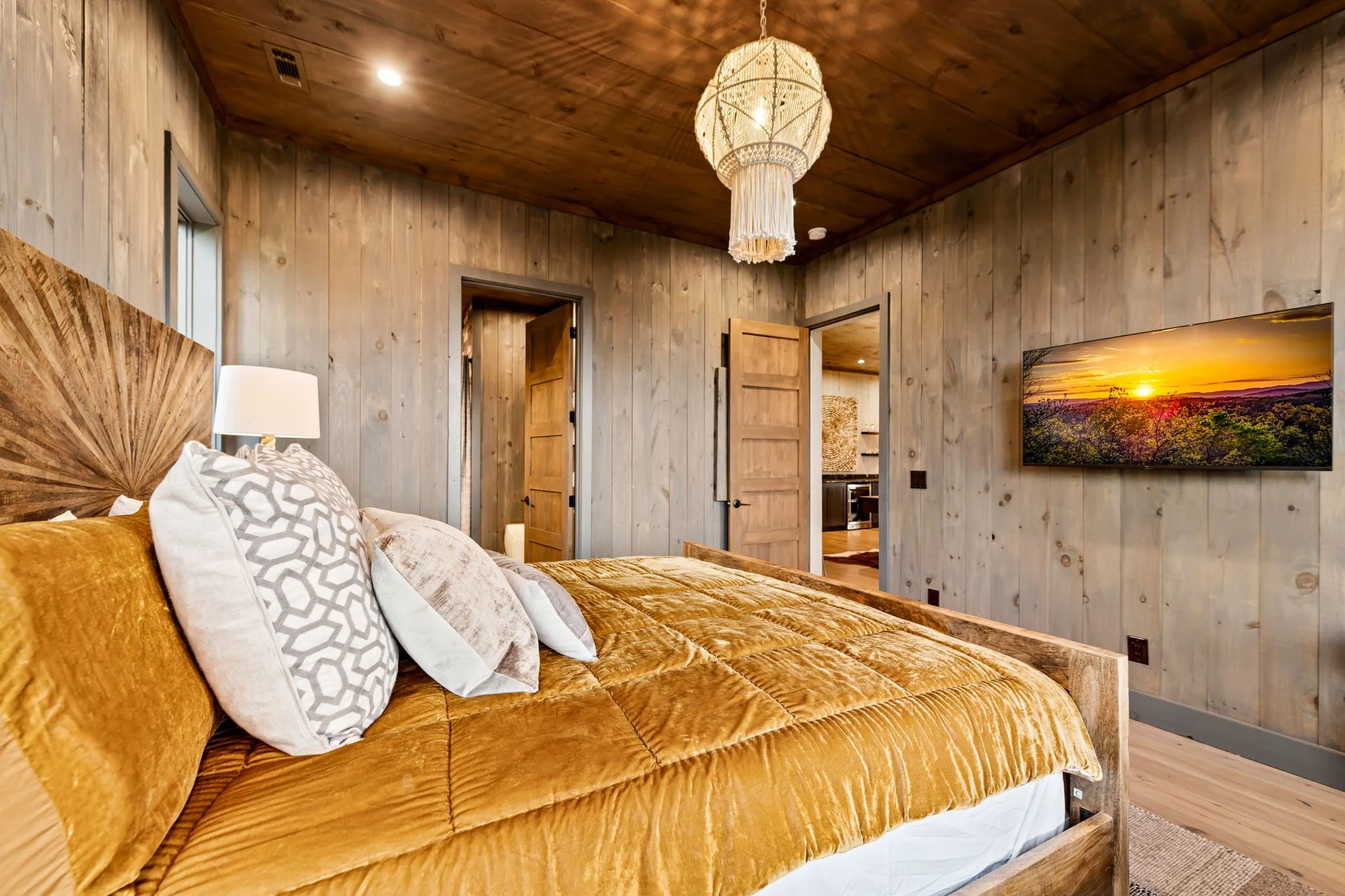 Relax in Bedroom 4, a stylish retreat featuring a beautifully crafted wood bed, plush bedding, designer chandelier, and Smart TV. Natural textures and elegant finishes create a cozy yet refined space perfect for unwinding after mountain adventures.