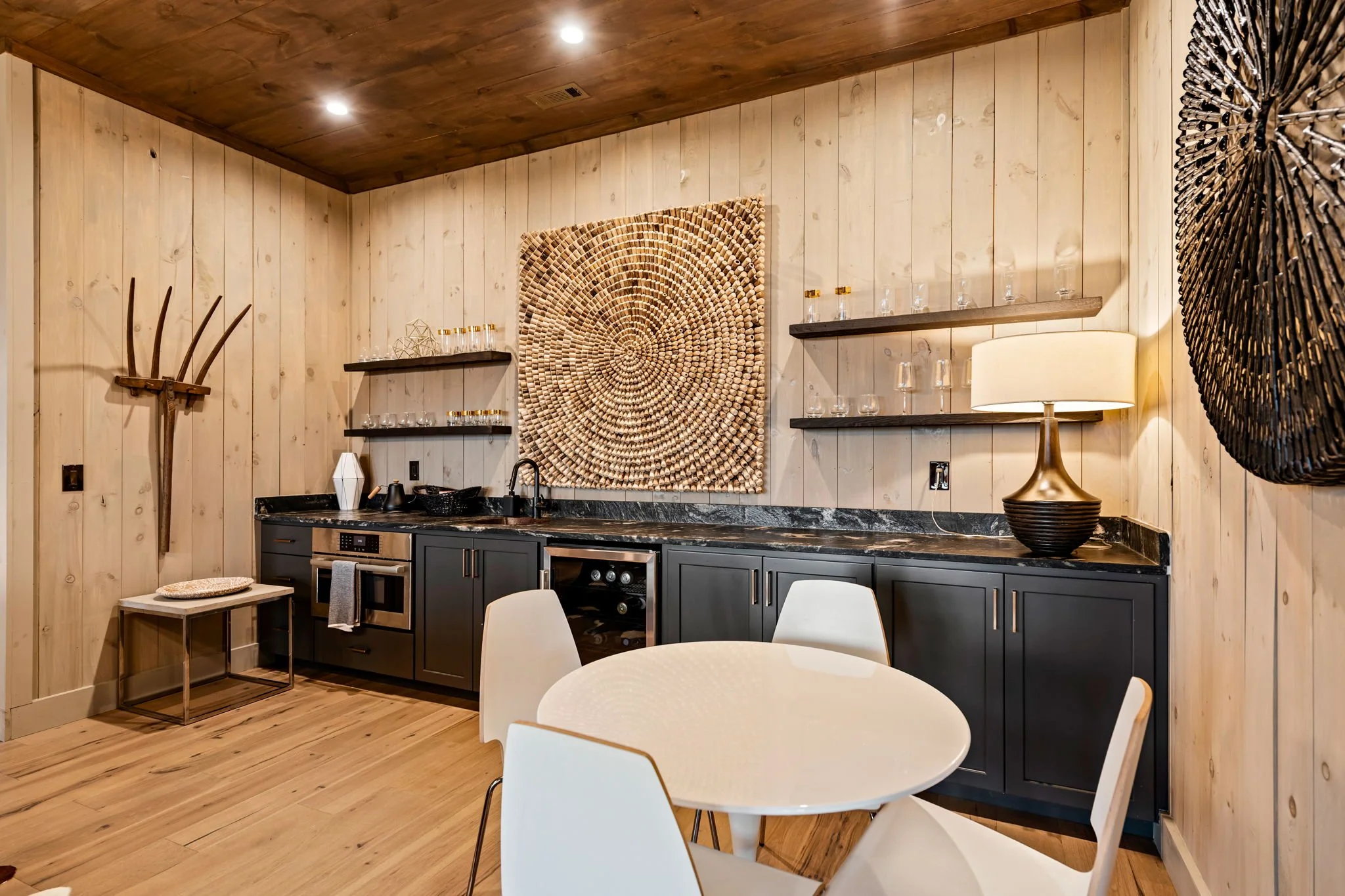 Mix & mingle at this stylish wet bar featuring a beverage fridge, sink, open shelving, wine storage, custom cabinetry, and café-style seating—perfect for cocktails, casual bites, and entertaining guests.