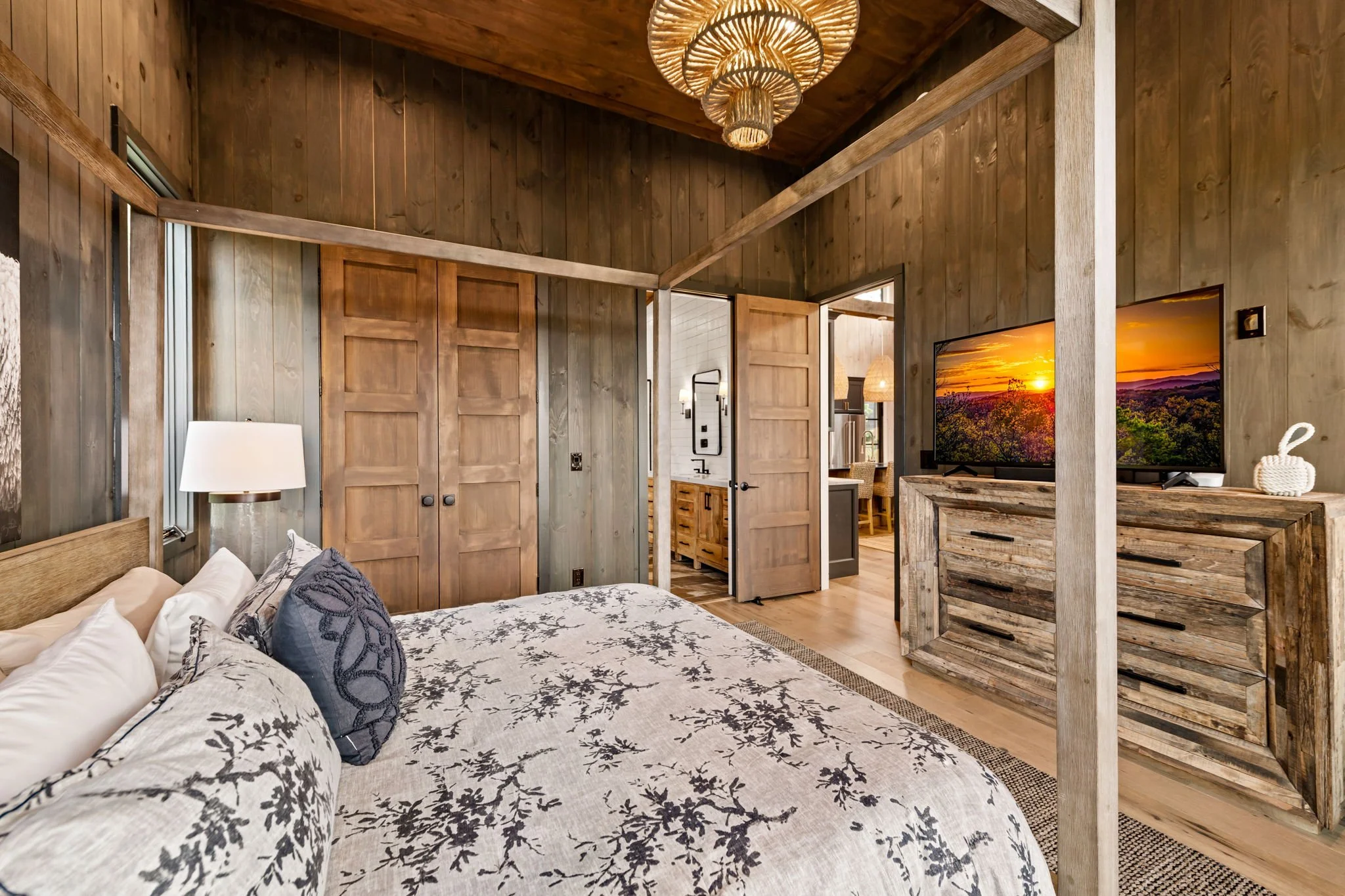 Retreat to the king suite featuring a stunning canopy bed, designer lighting, rich wood finishes, and a large smart TV. Spacious and refined, this elegant bedroom offers a peaceful escape with direct access to the beautifully appointed ensuite bath.