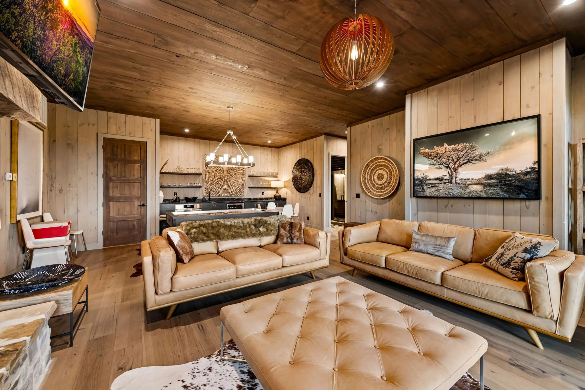 Relax in this spacious lounge featuring plush leather sofas, Smart TV, stone fireplace, designer lighting, open-concept seating, and a nearby wet bar & game area—a perfect gathering space for entertainment and cozy evenings.