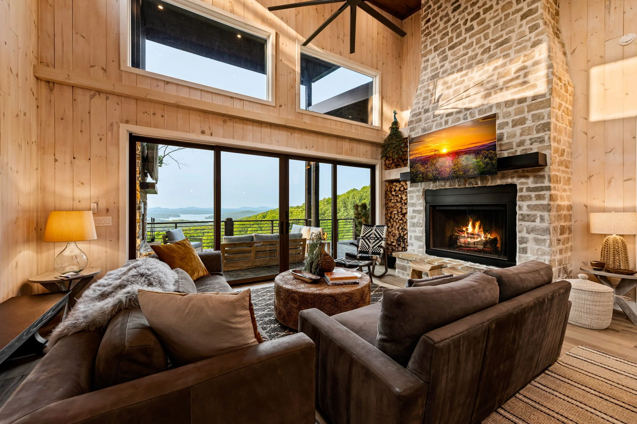 Relax in the stunning great room with soaring ceilings, a dramatic stone fireplace, and designer furnishings. Floor-to-ceiling doors open to the terrace, revealing sweeping mountain and lake views that elevate every moment of this refined retreat.